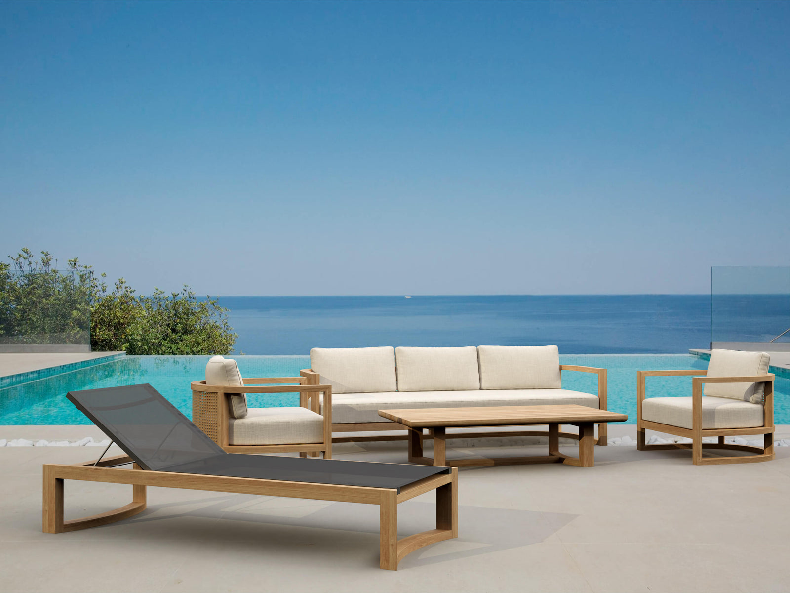 Outdoor furniture set with lounge chair, sofa, and table by a pool with ocean view.