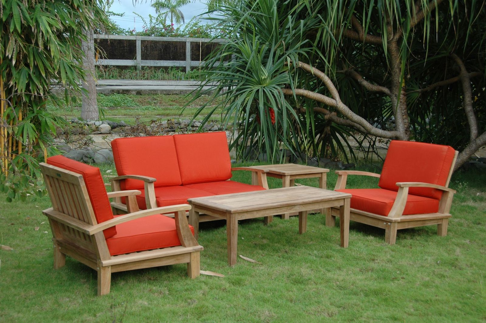 Outdoor furniture set with red cushions on a grassy area