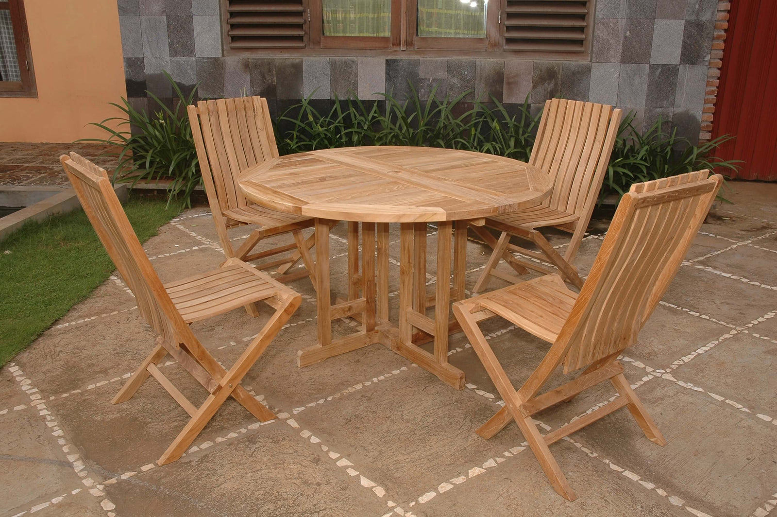 Wooden outdoor dining set with table and chairs on a stone patio.