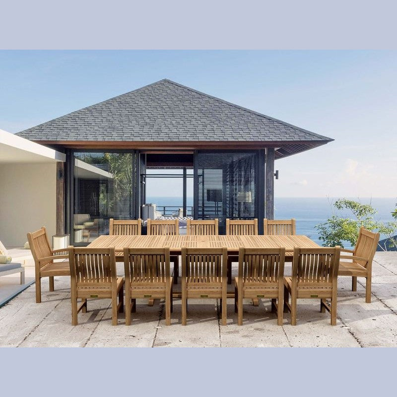 Wooden outdoor dining set with chairs on a patio area with a house and ocean view.
