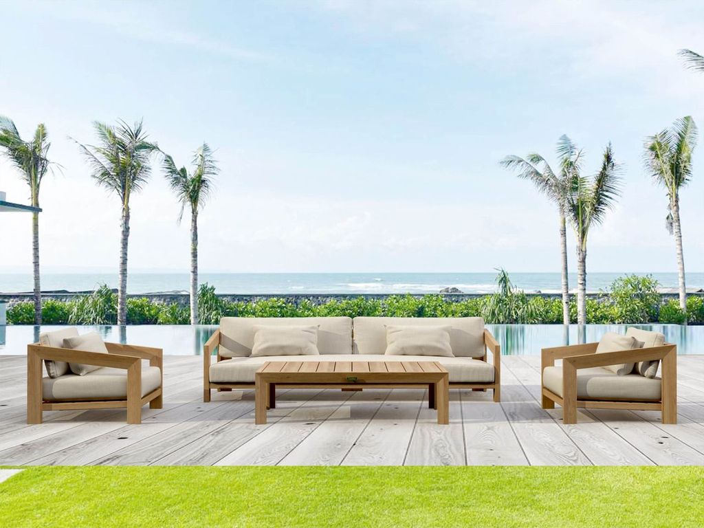 Outdoor furniture set with beige cushions on a wooden deck by a pool with palm trees in the background.