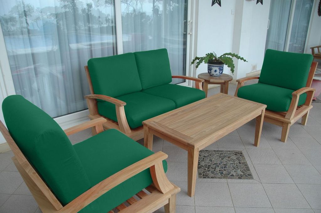 Green cushioned outdoor furniture set with a wooden table on a patio.