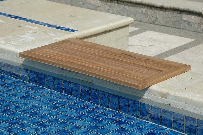 Wooden diving board on a pool deck with blue tiles