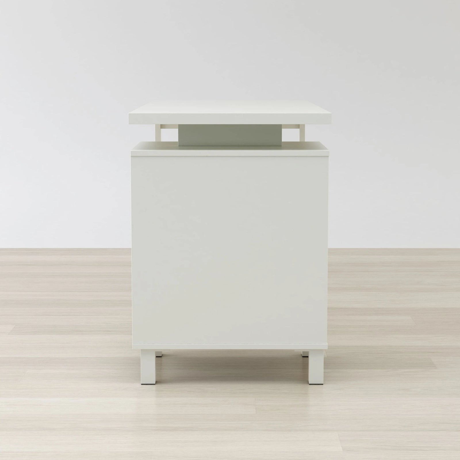 White nightstand with a green accent on a wooden floor and white wall background