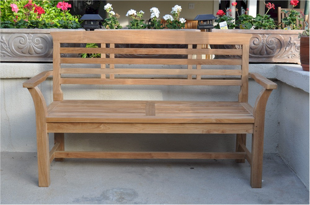 Wooden bench on a patio with flowers in the background