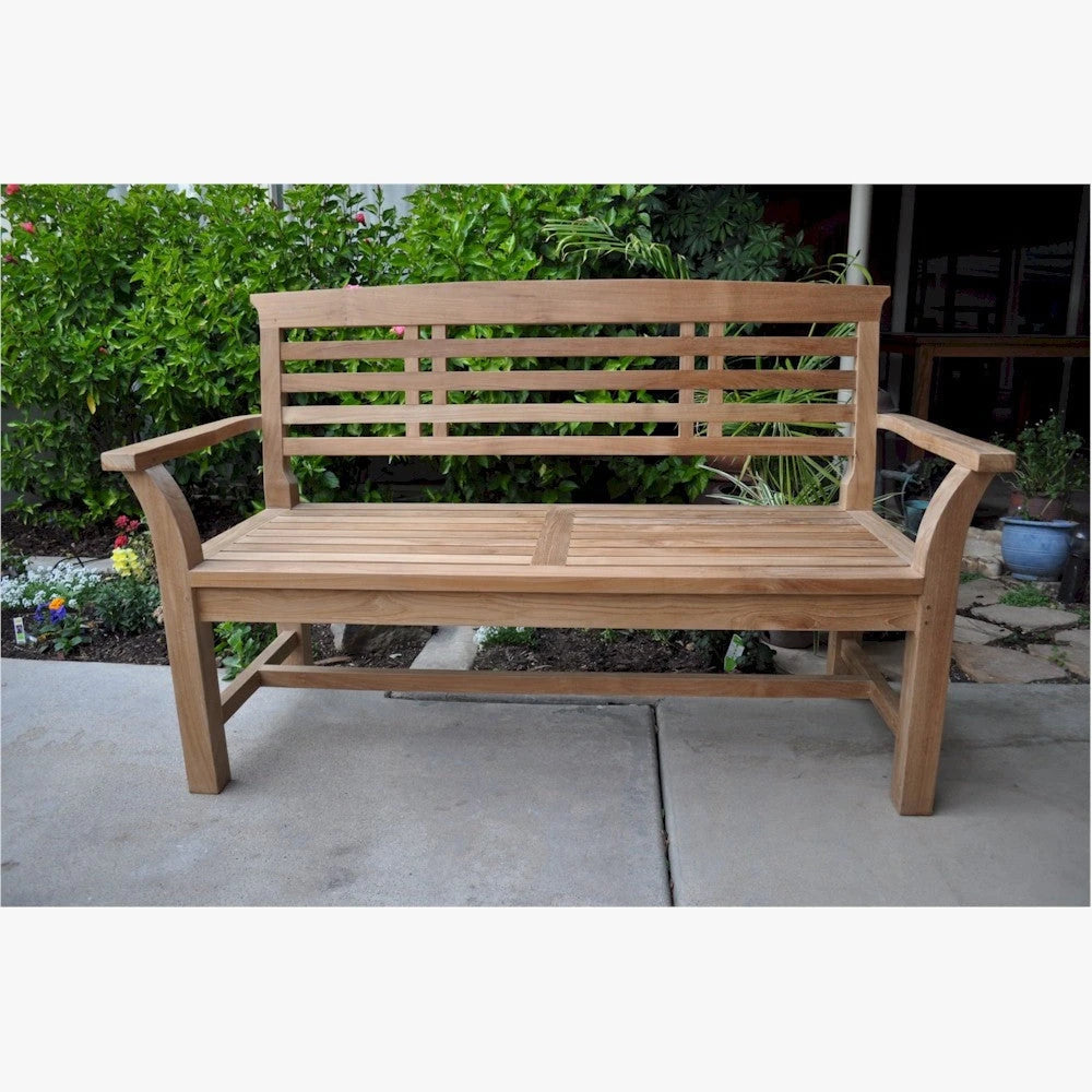 Wooden bench on a patio with greenery in the background