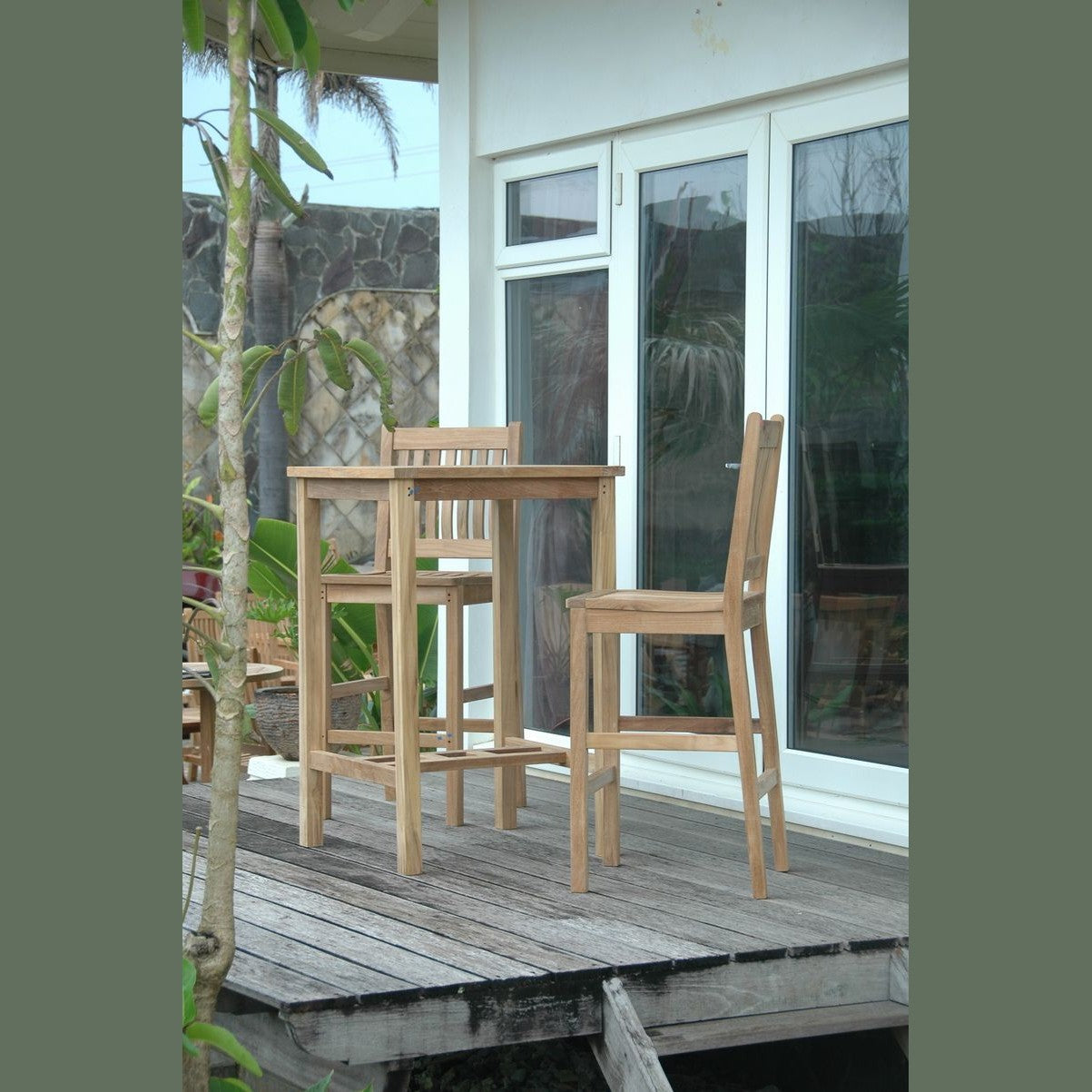 Wooden outdoor dining set on a wooden deck with a glass door in the background.