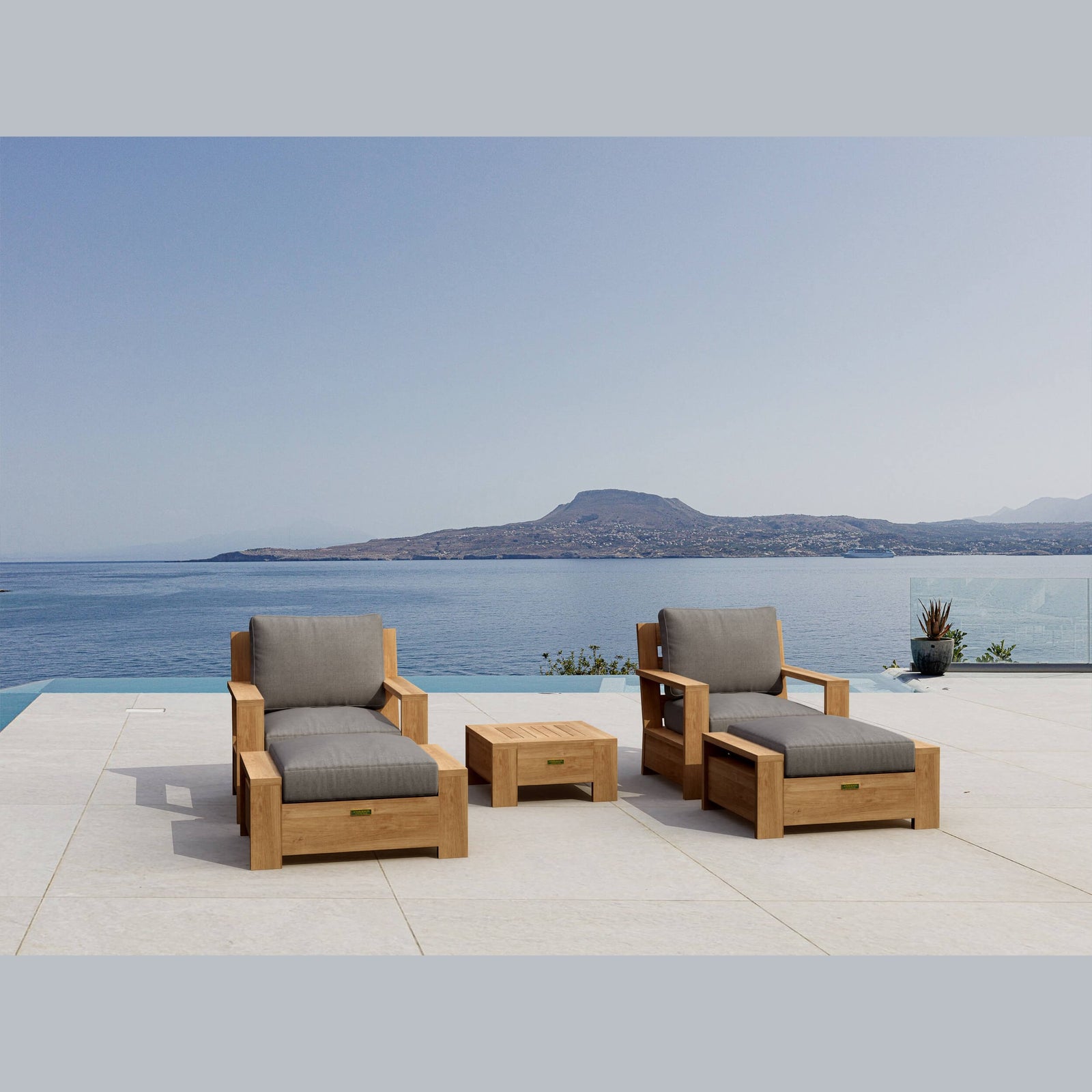 Outdoor furniture set with gray cushions by a pool with a mountain view.