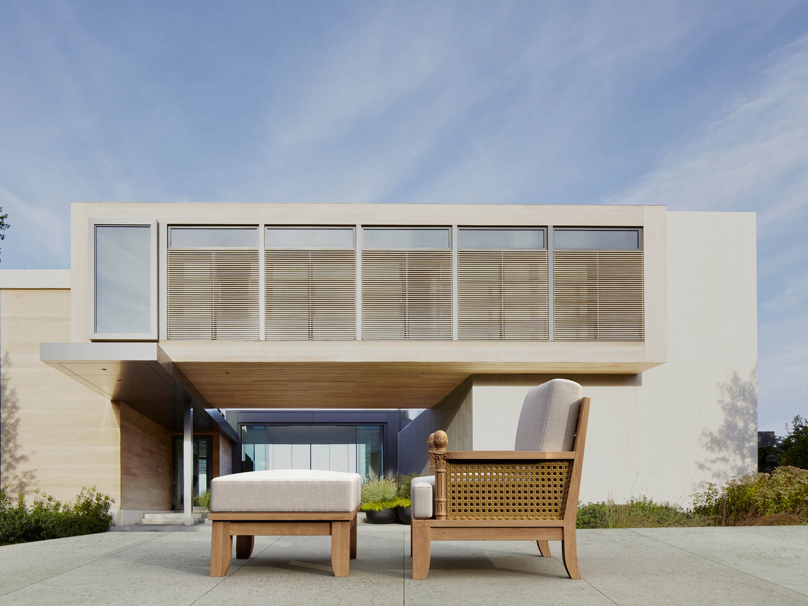 Modern outdoor furniture set in front of a contemporary house with a clear blue sky.