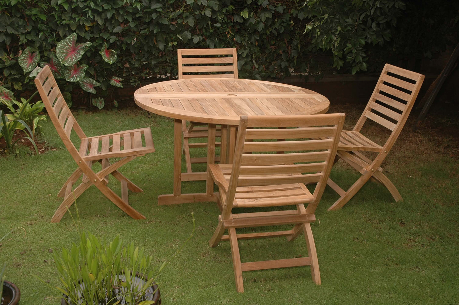 Wooden outdoor table with four matching chairs on a grassy area.