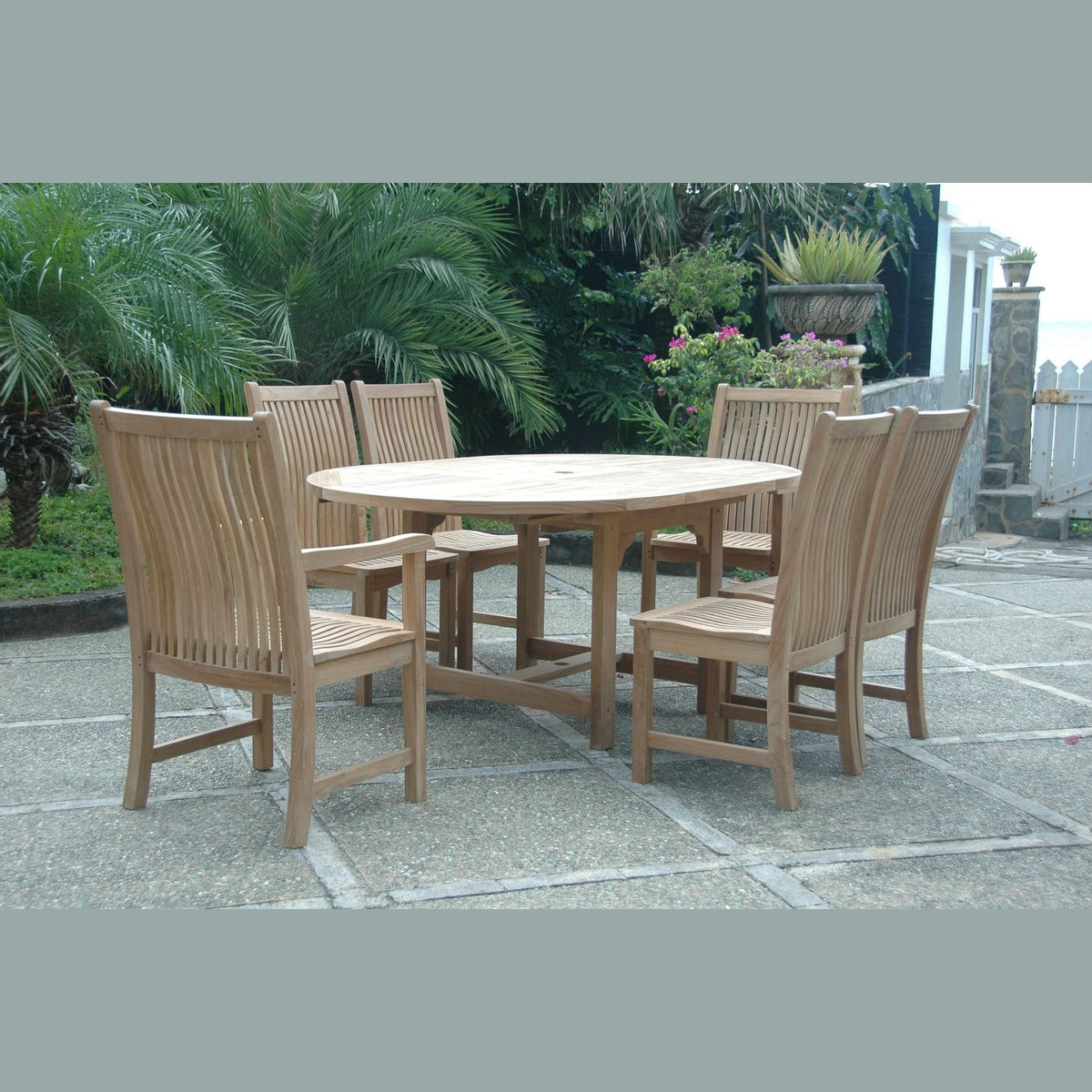 Wooden outdoor dining set with round table and six chairs on a stone patio.