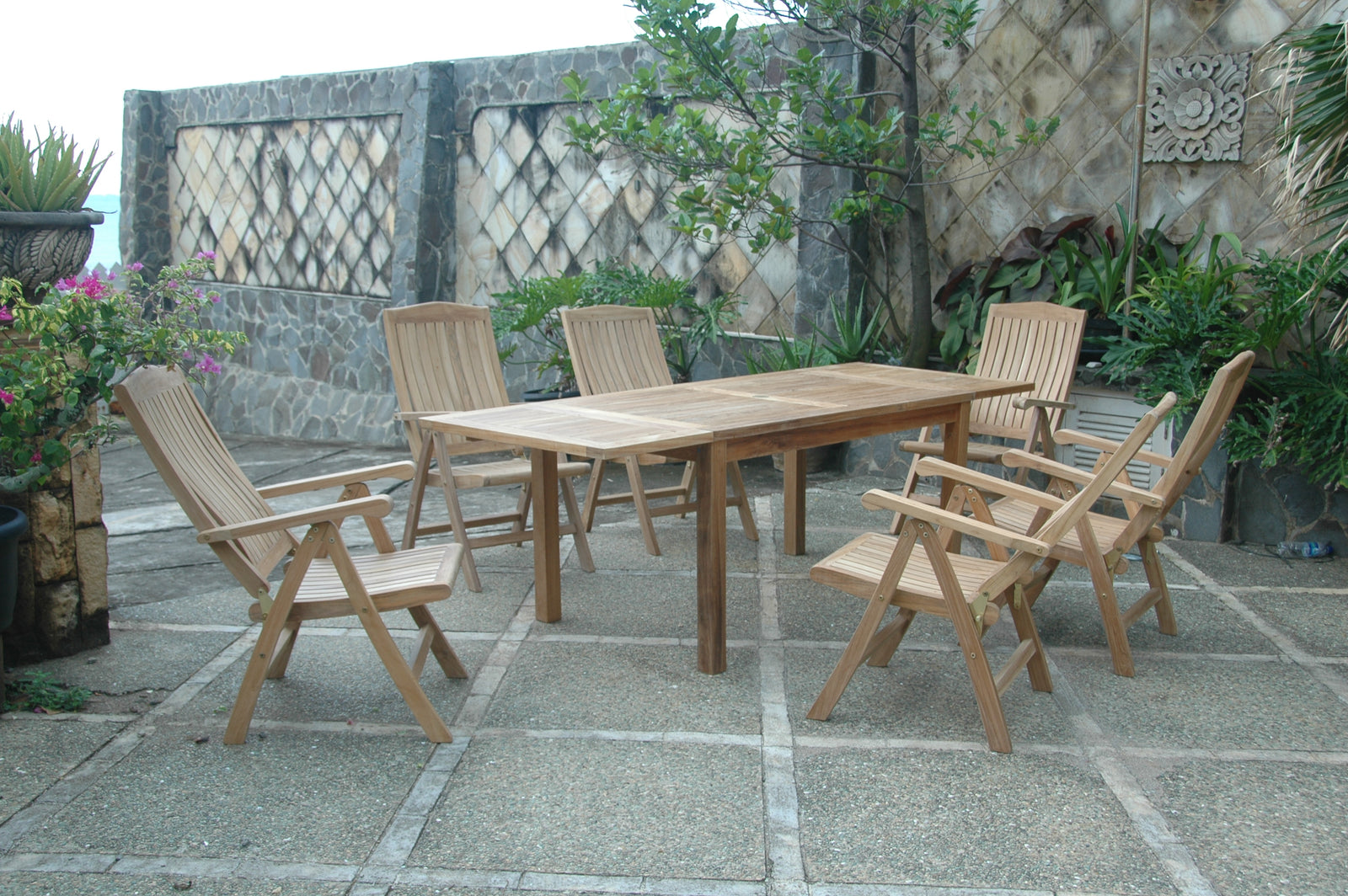 Wooden outdoor dining set with chairs on a stone patio