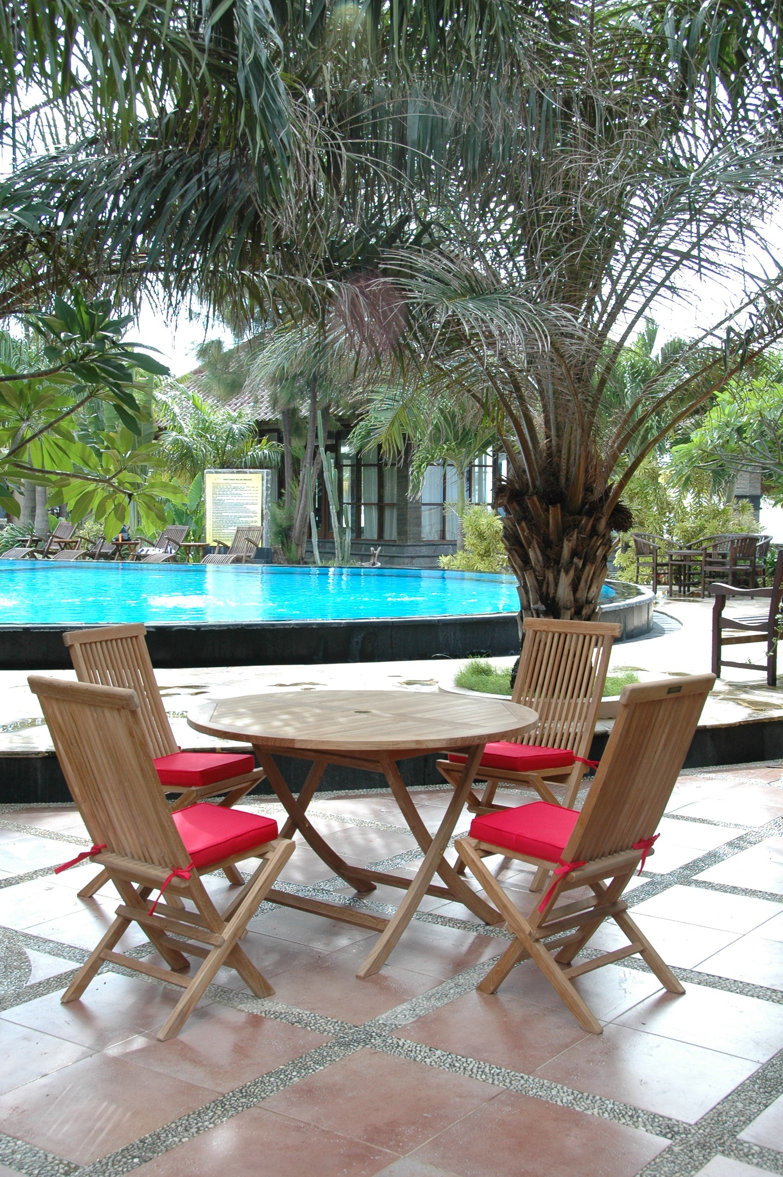 Wooden outdoor table with four chairs near a poolside area