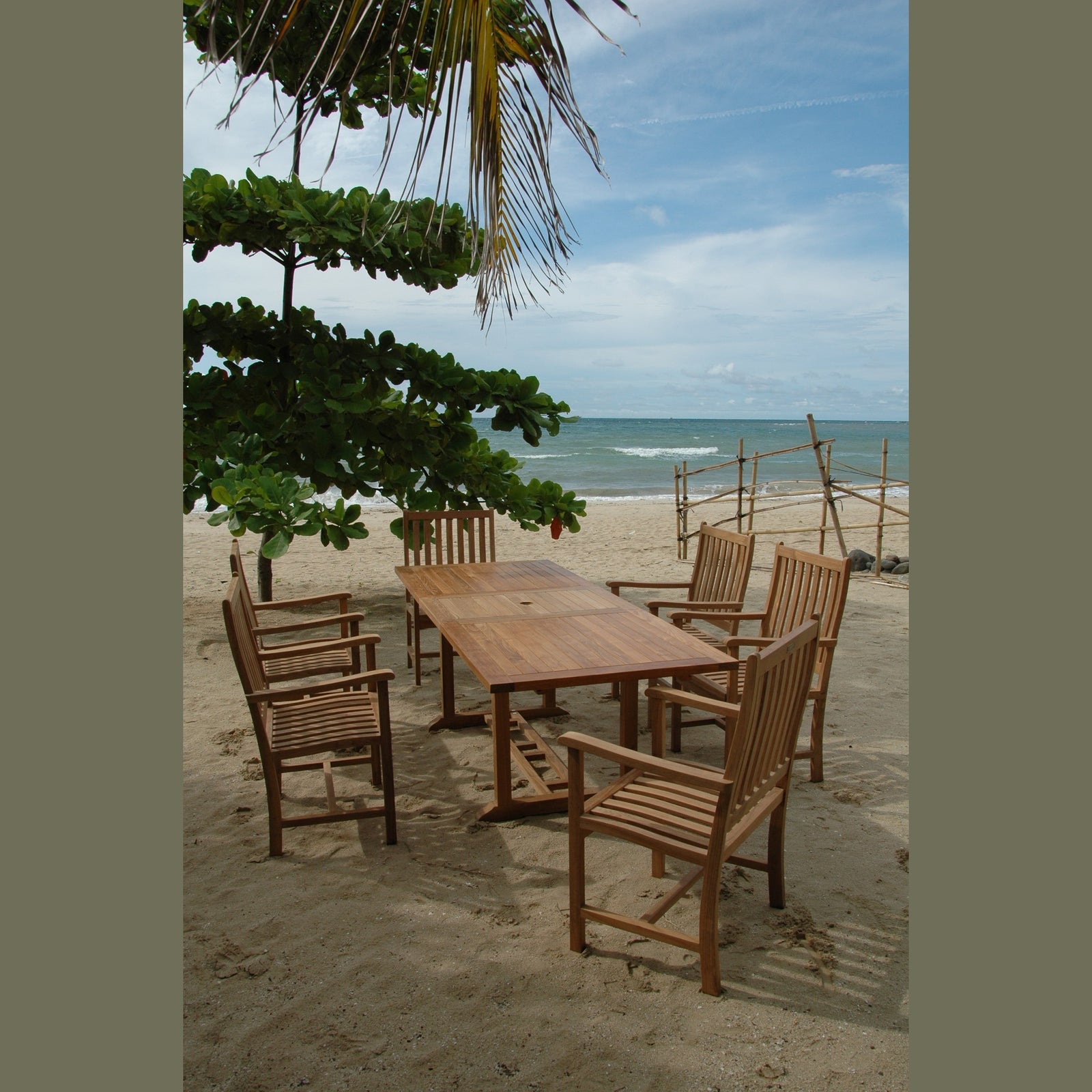 Wooden dining set on a sandy beach with ocean and sky in the background