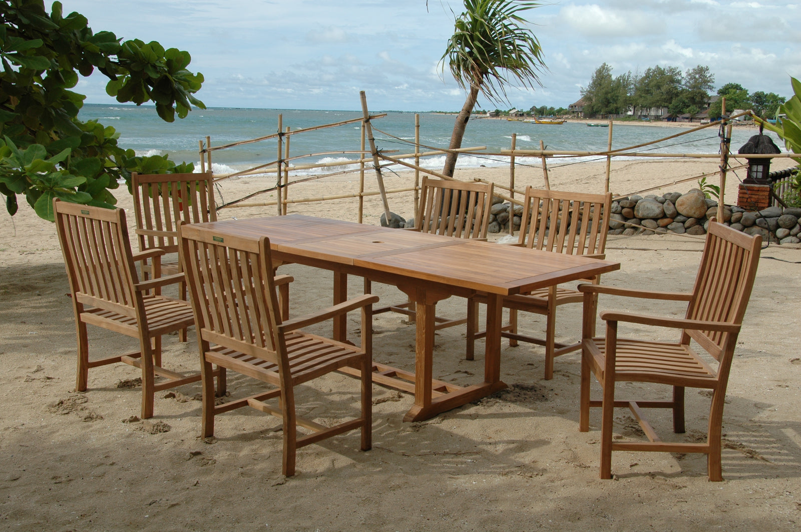 Wooden outdoor dining set on a sandy beach with ocean view