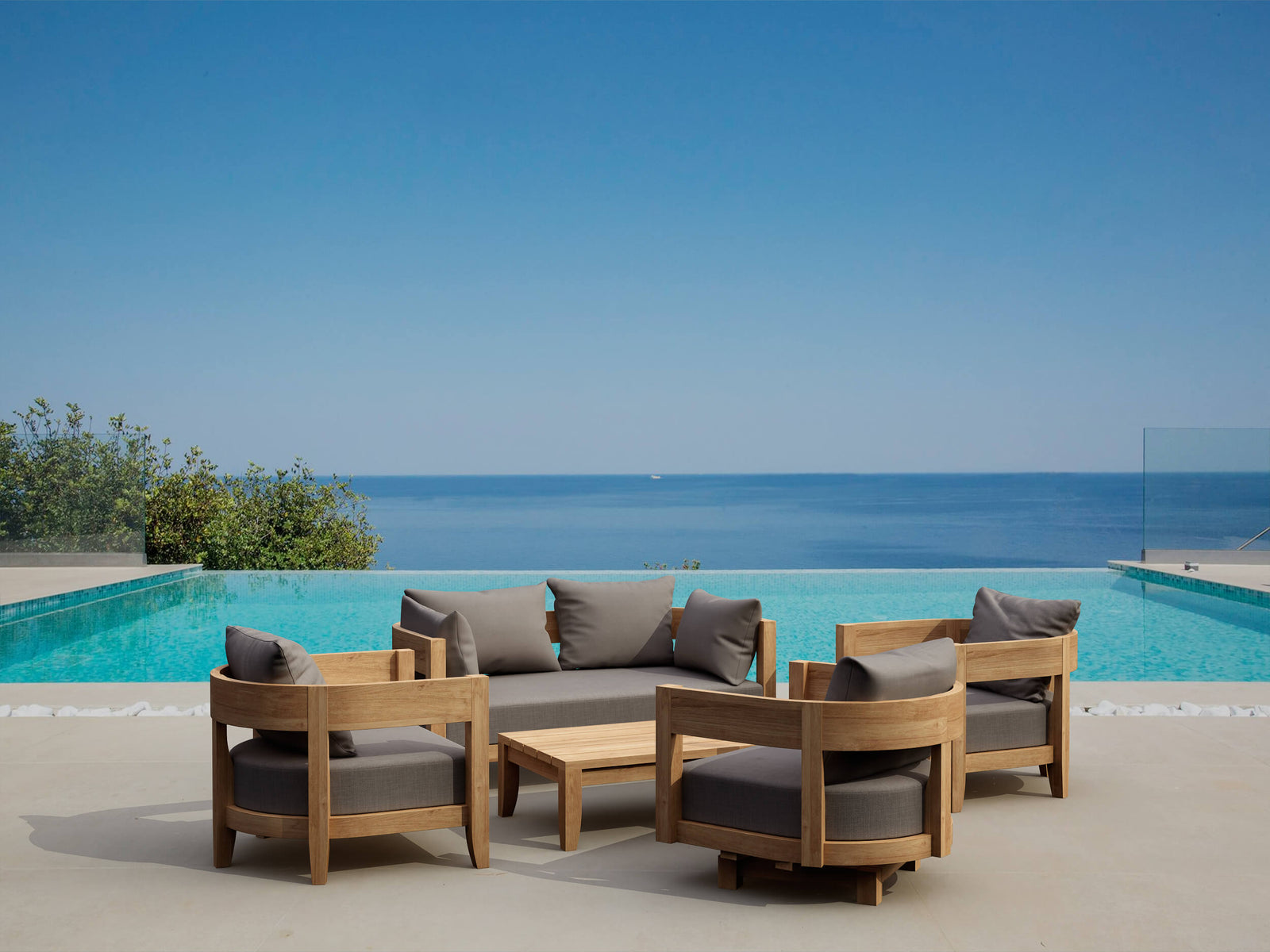 Outdoor furniture set with gray cushions by a pool with ocean view