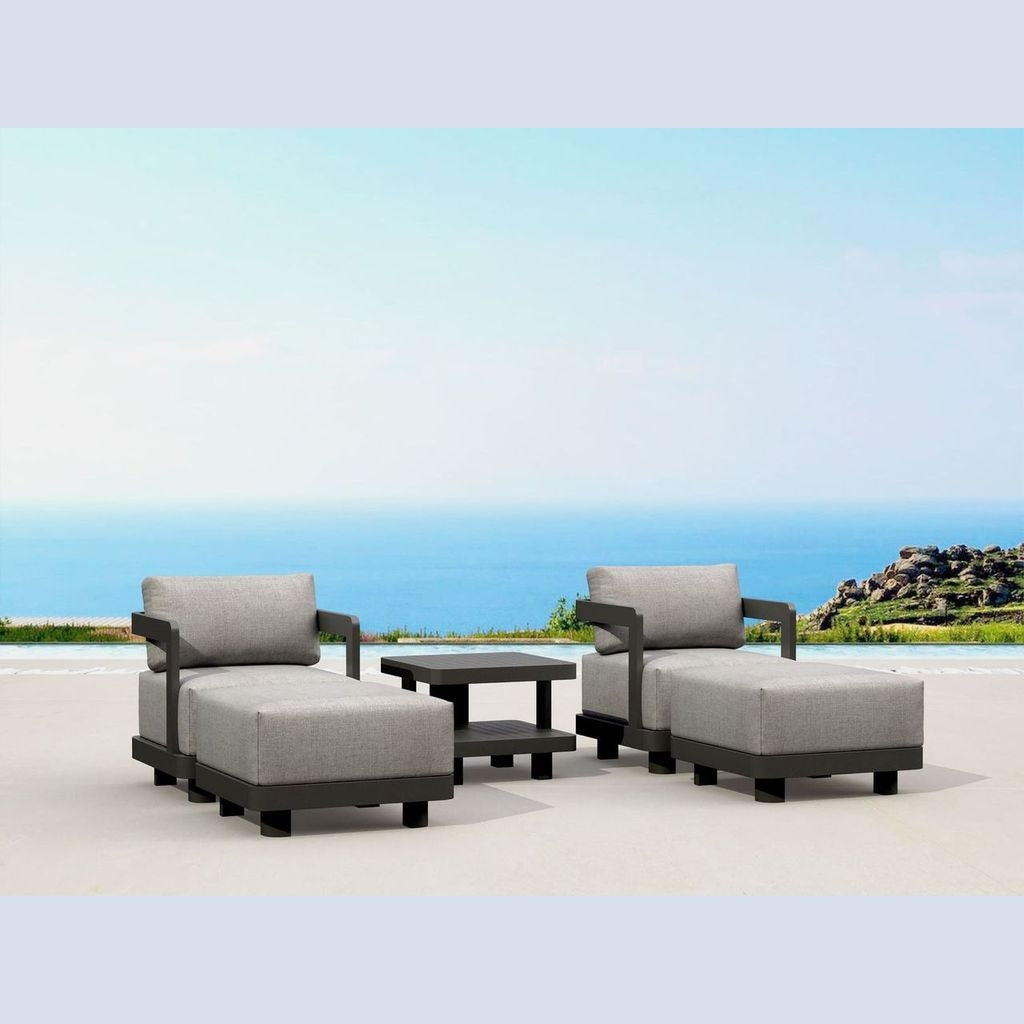 Outdoor patio furniture set with gray cushions on a sandy beach with ocean view.