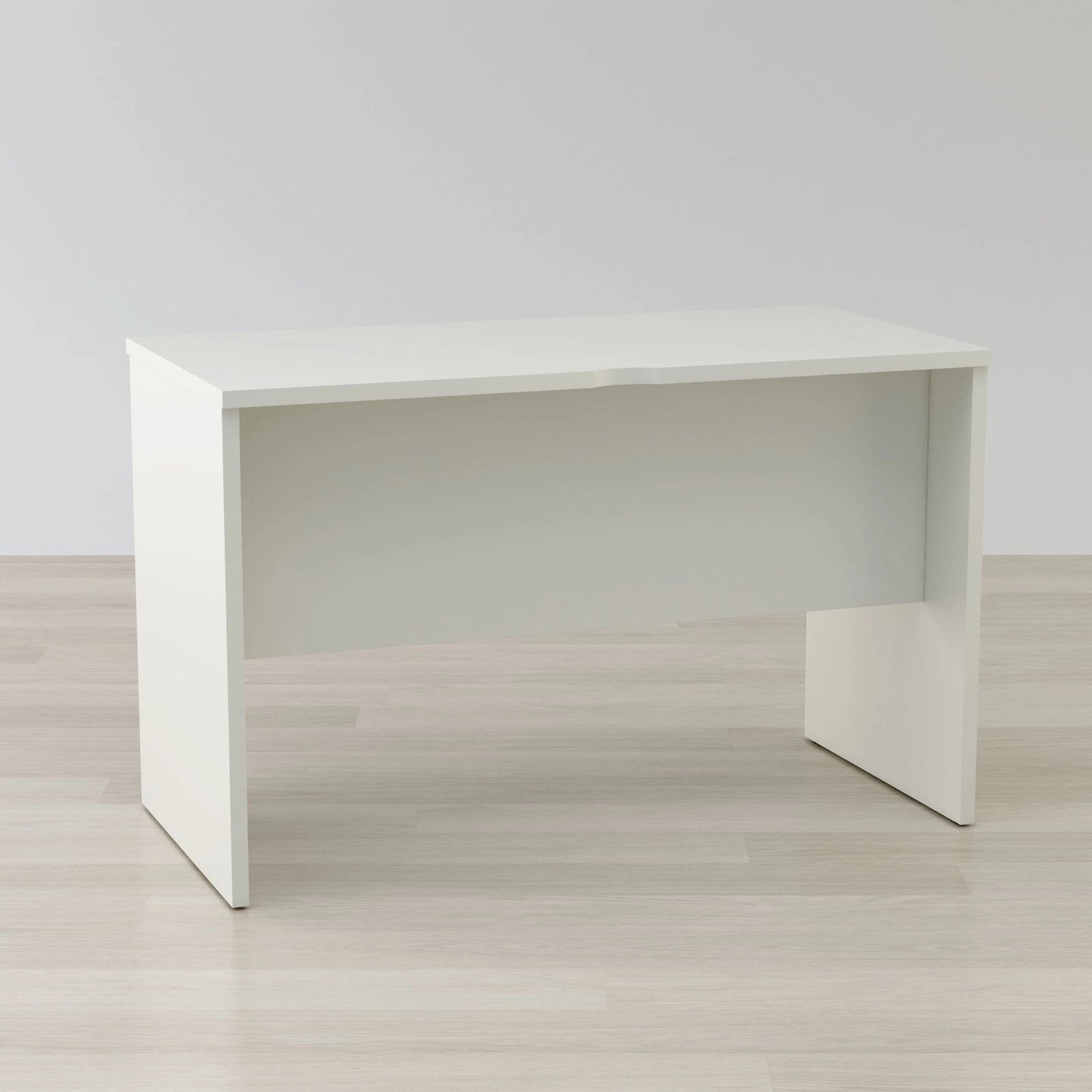 White desk on a light wooden floor with a plain white wall background