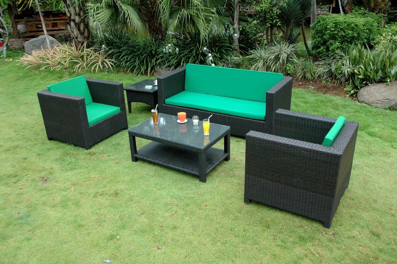 Outdoor furniture set with green cushions on a grassy area