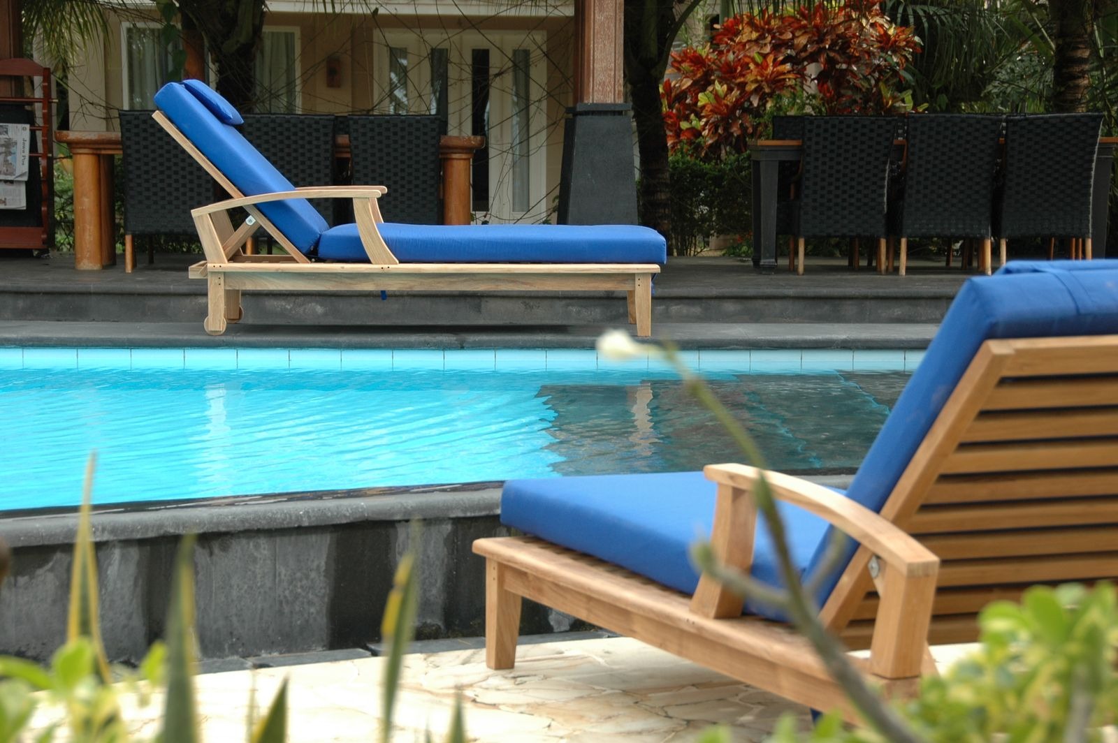 Blue lounge chairs by a pool with a tropical setting