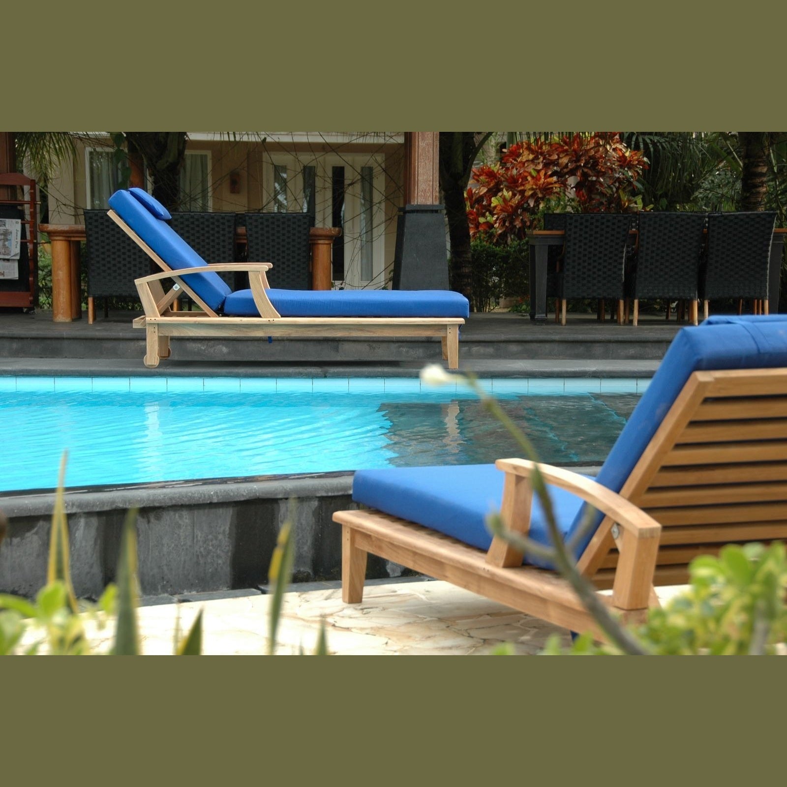Blue lounge chairs by a pool with a tropical setting