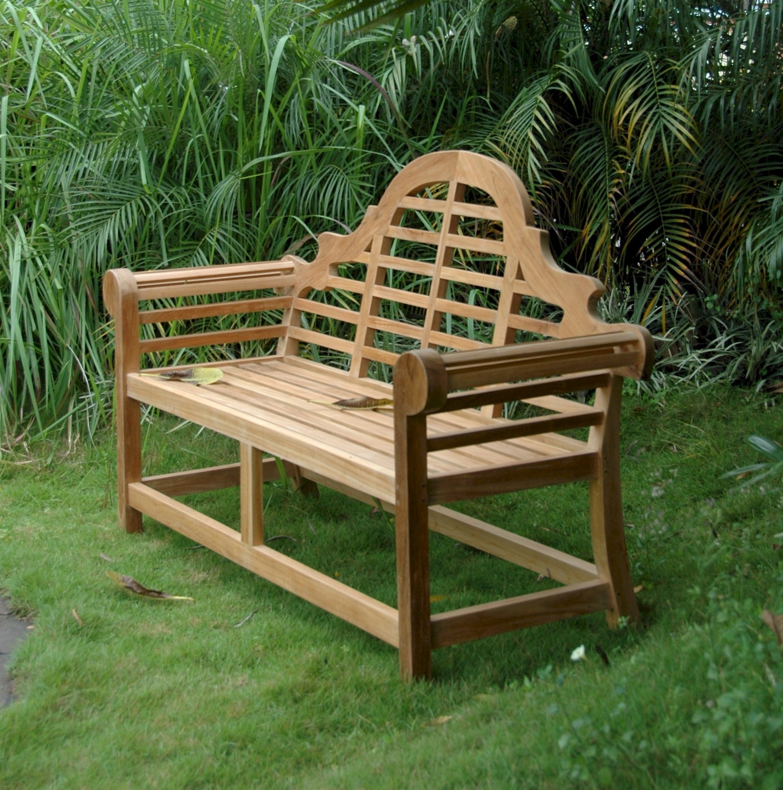 Wooden garden bench with intricate backrest in a grassy area with greenery