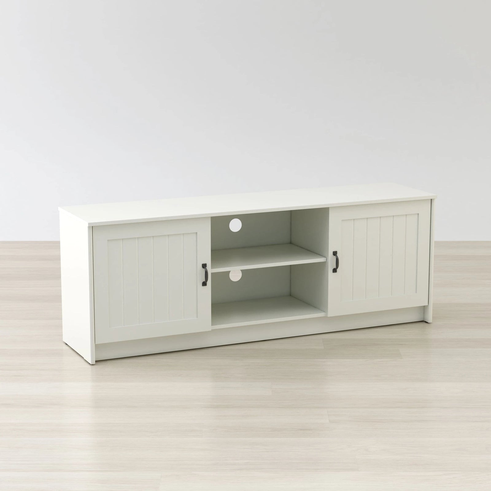 White TV stand with sliding doors on a light wooden floor and white wall background