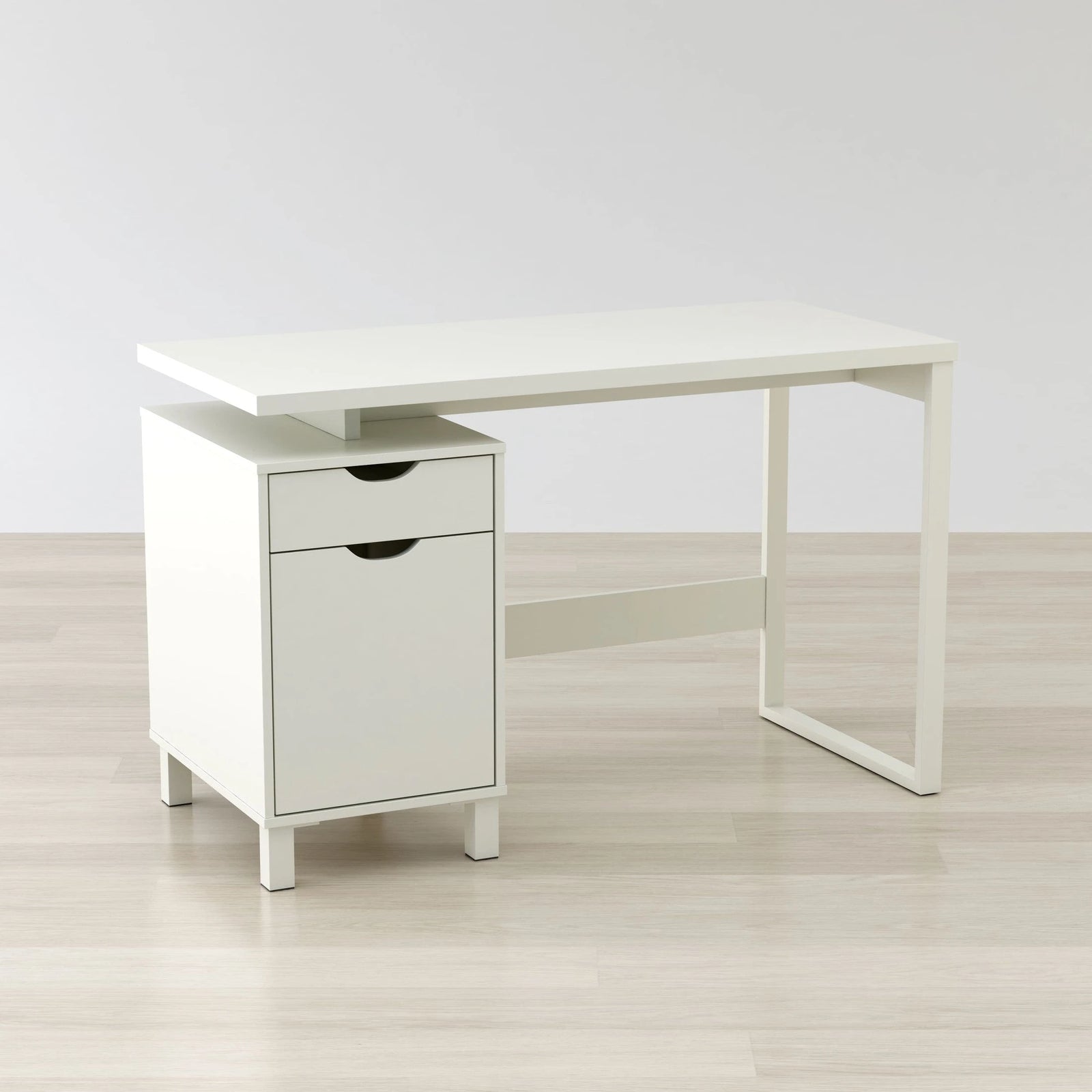 White desk with a drawer on a light wooden floor and white wall background