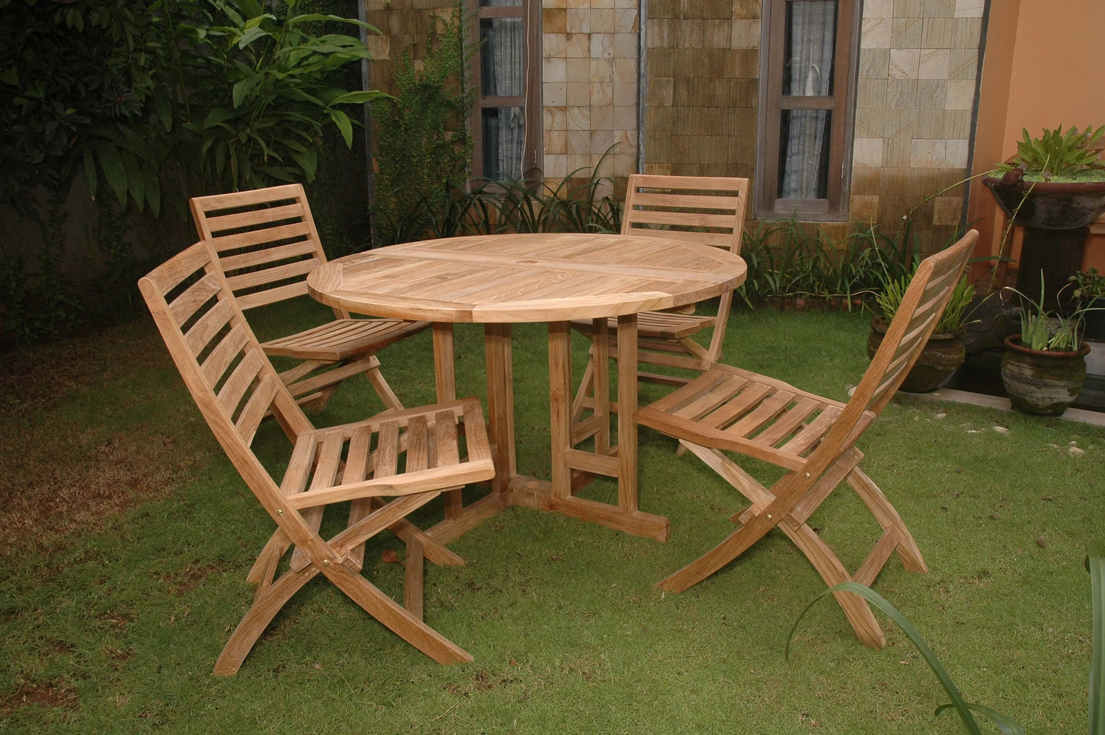 Wooden outdoor table with four matching chairs on a grassy area.