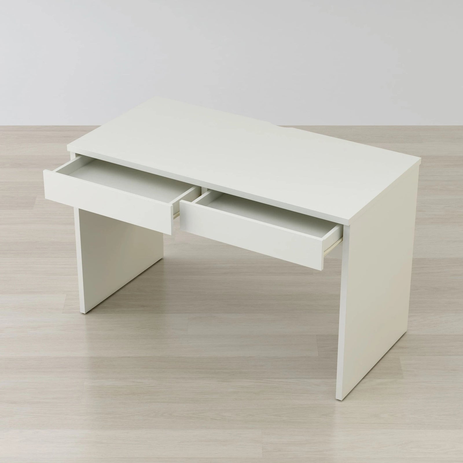 White desk with two drawers on a light wooden floor.
