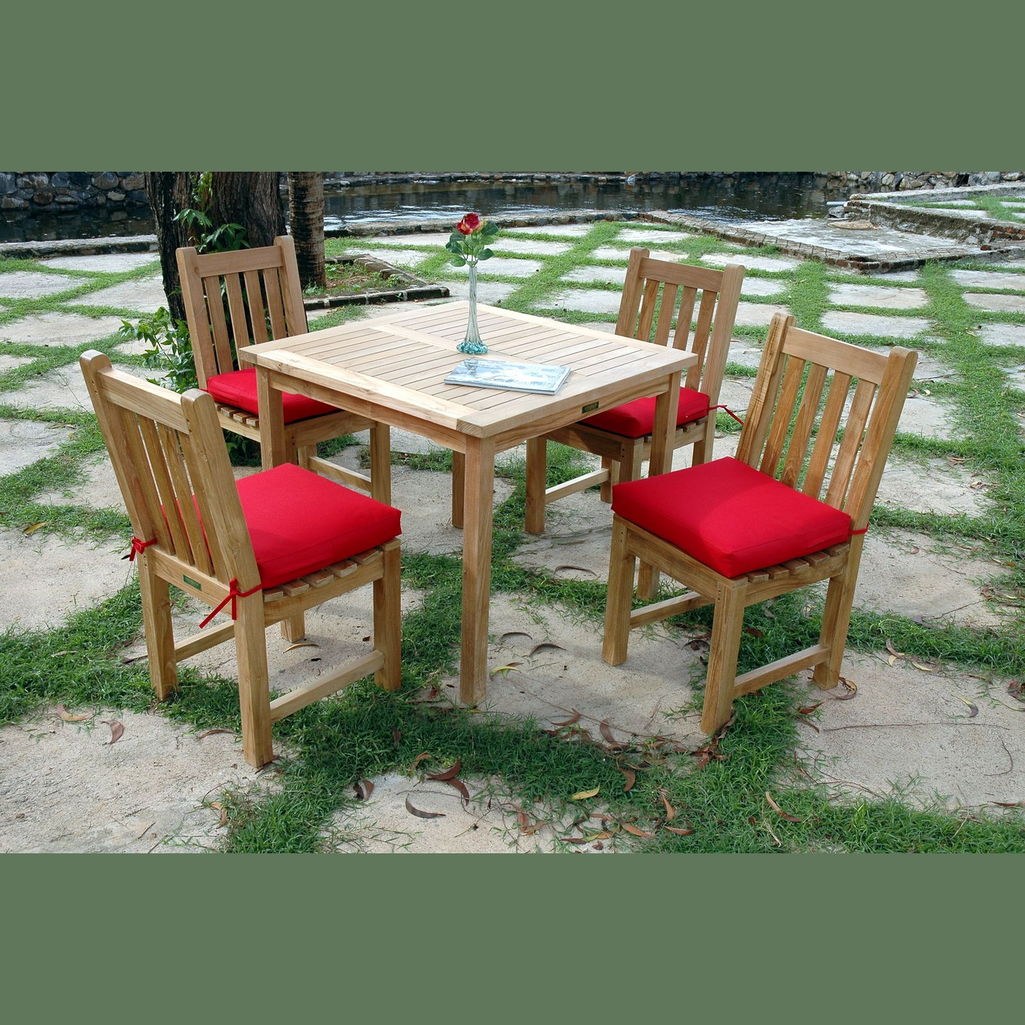Wooden outdoor table set with four chairs and red cushions on a stone patio.