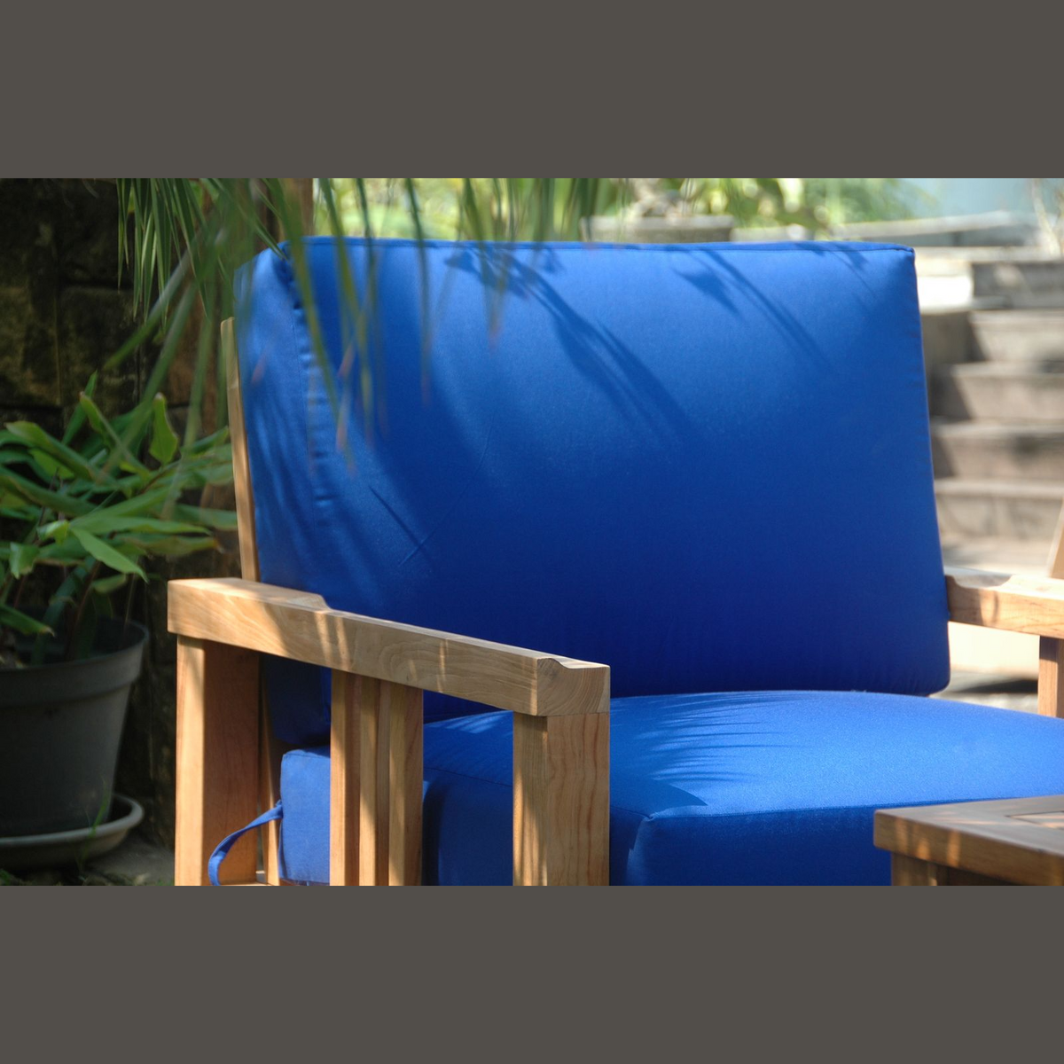Blue cushioned chair with wooden frame in an outdoor setting