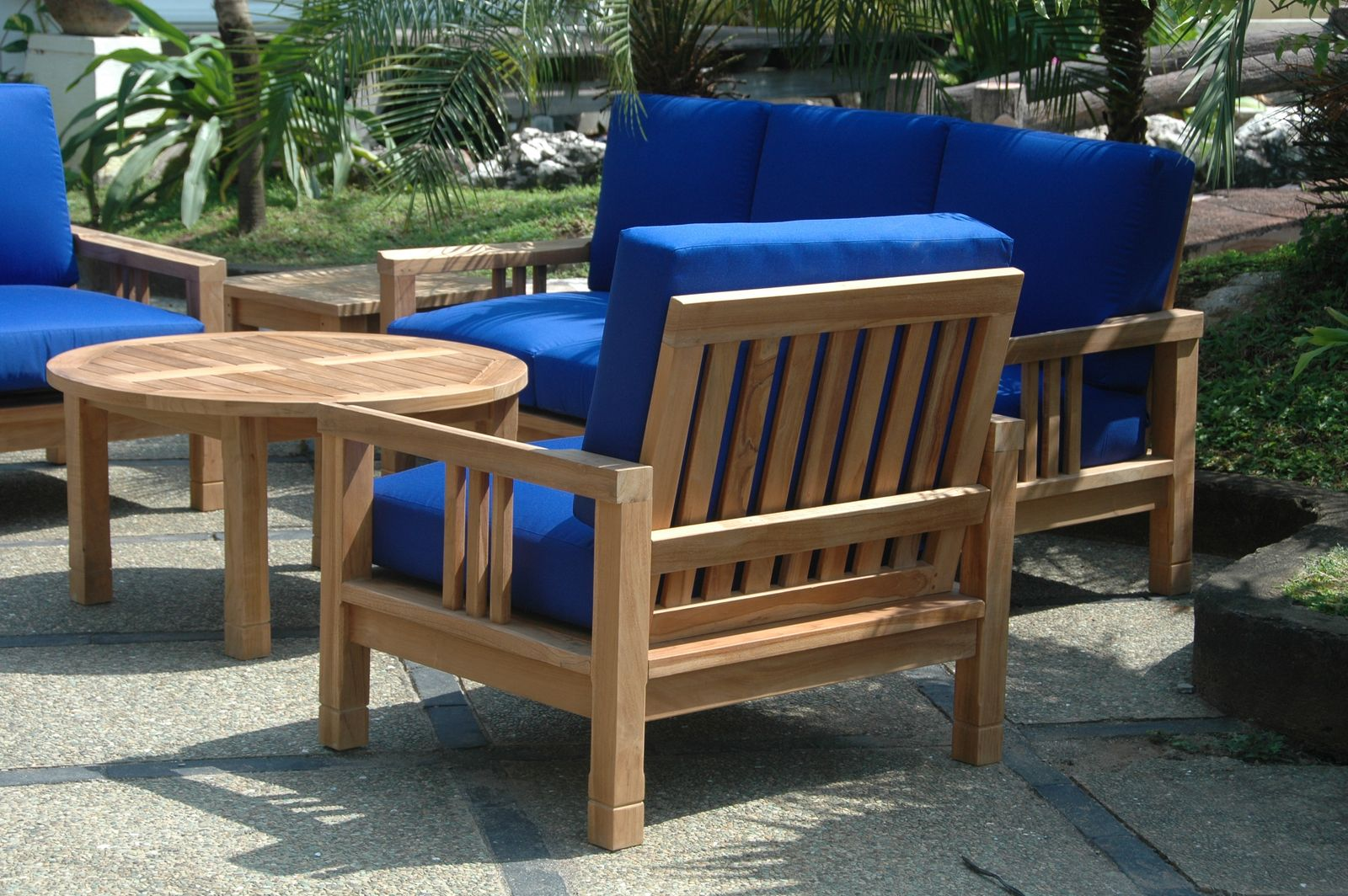 Outdoor furniture set with blue cushions and a wooden table on a patio.