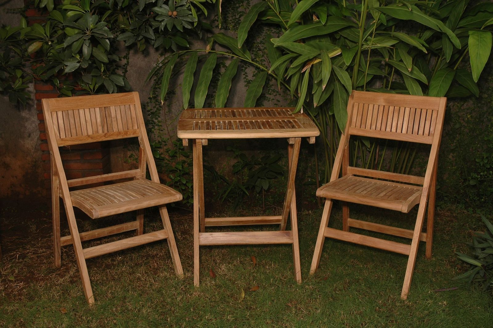 Wooden outdoor furniture set with two chairs and a small table against a green leafy background.