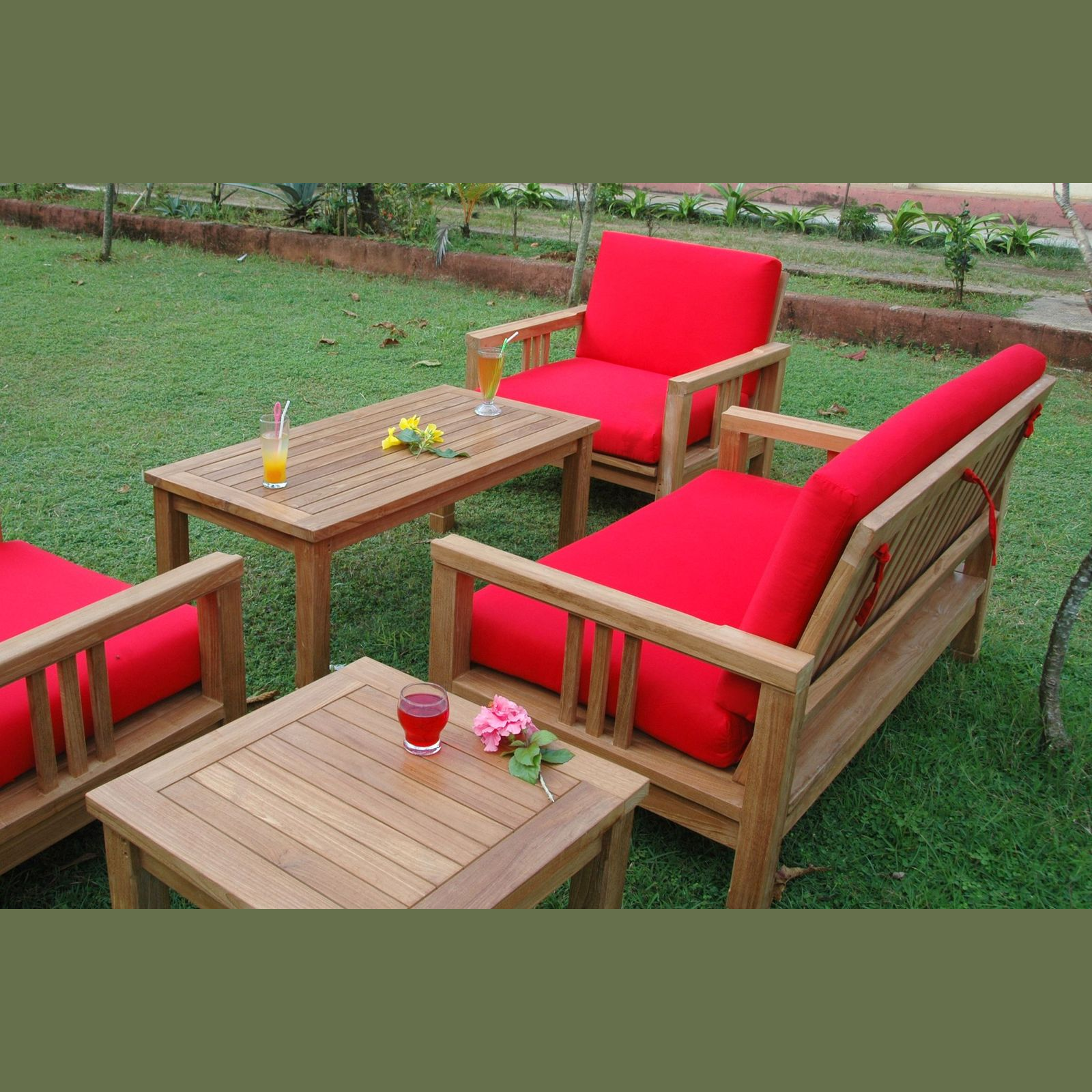 Outdoor furniture set with red cushions on a grassy area