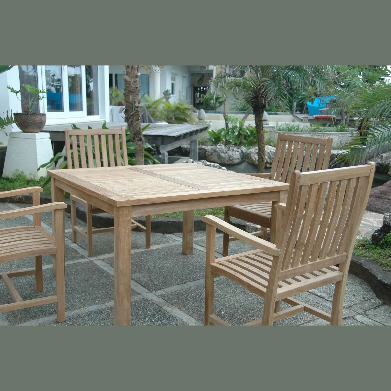 Wooden outdoor dining table with chairs on a stone patio