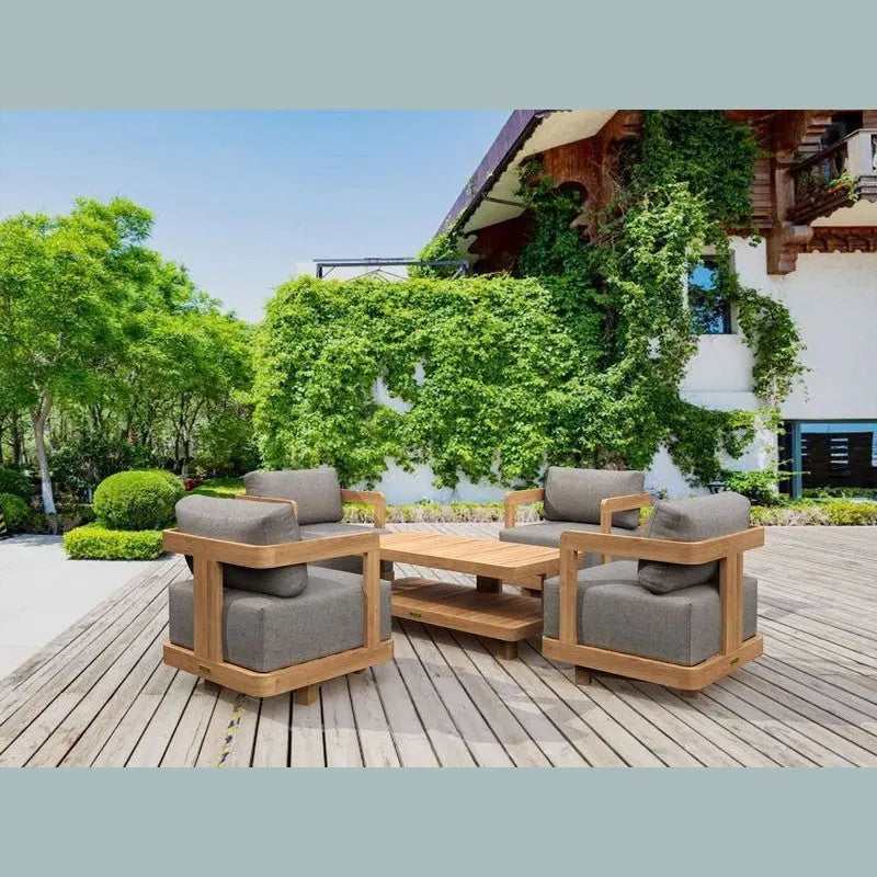 Outdoor patio furniture set on a wooden deck with greenery and a building in the background.