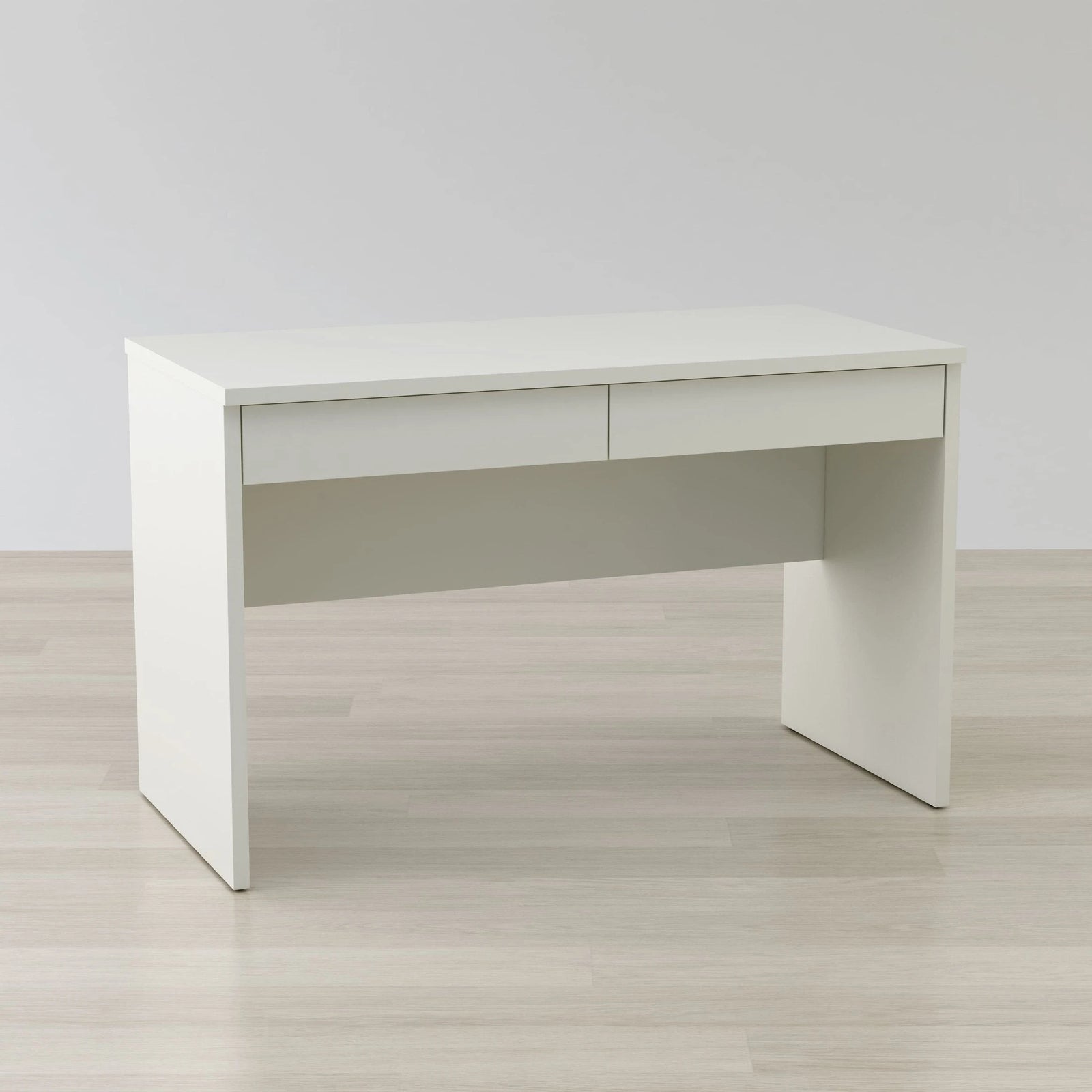 White office desk on a light wooden floor with a plain white wall background