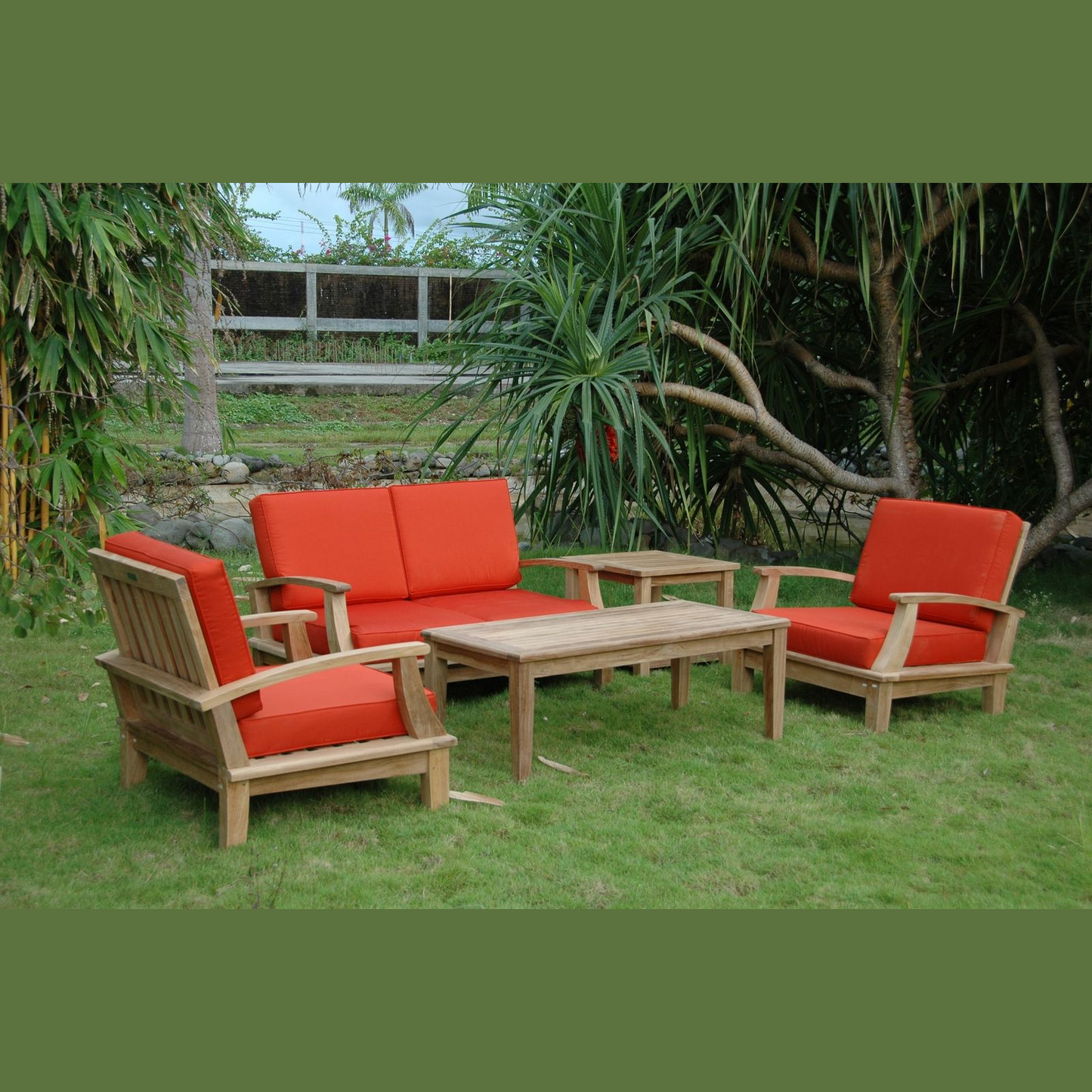 Outdoor furniture set with red cushions on a grassy area