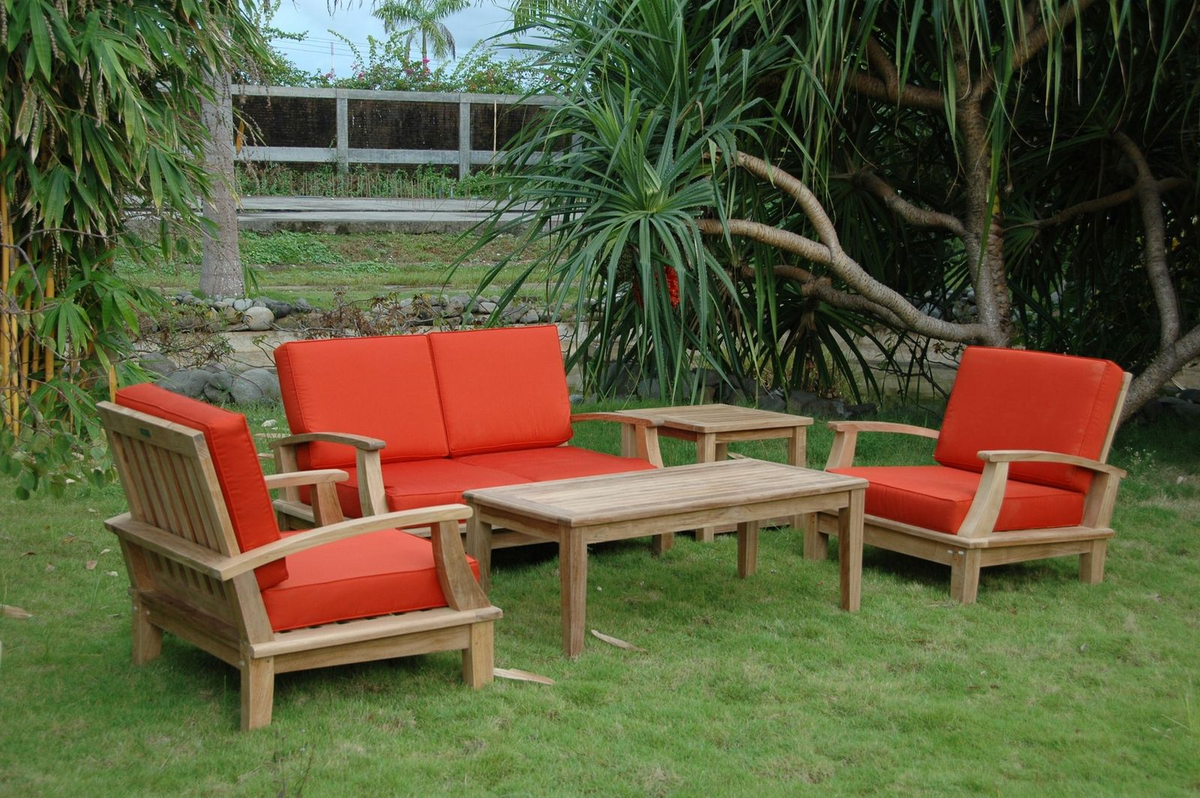 Outdoor furniture set with red cushions on a grassy area