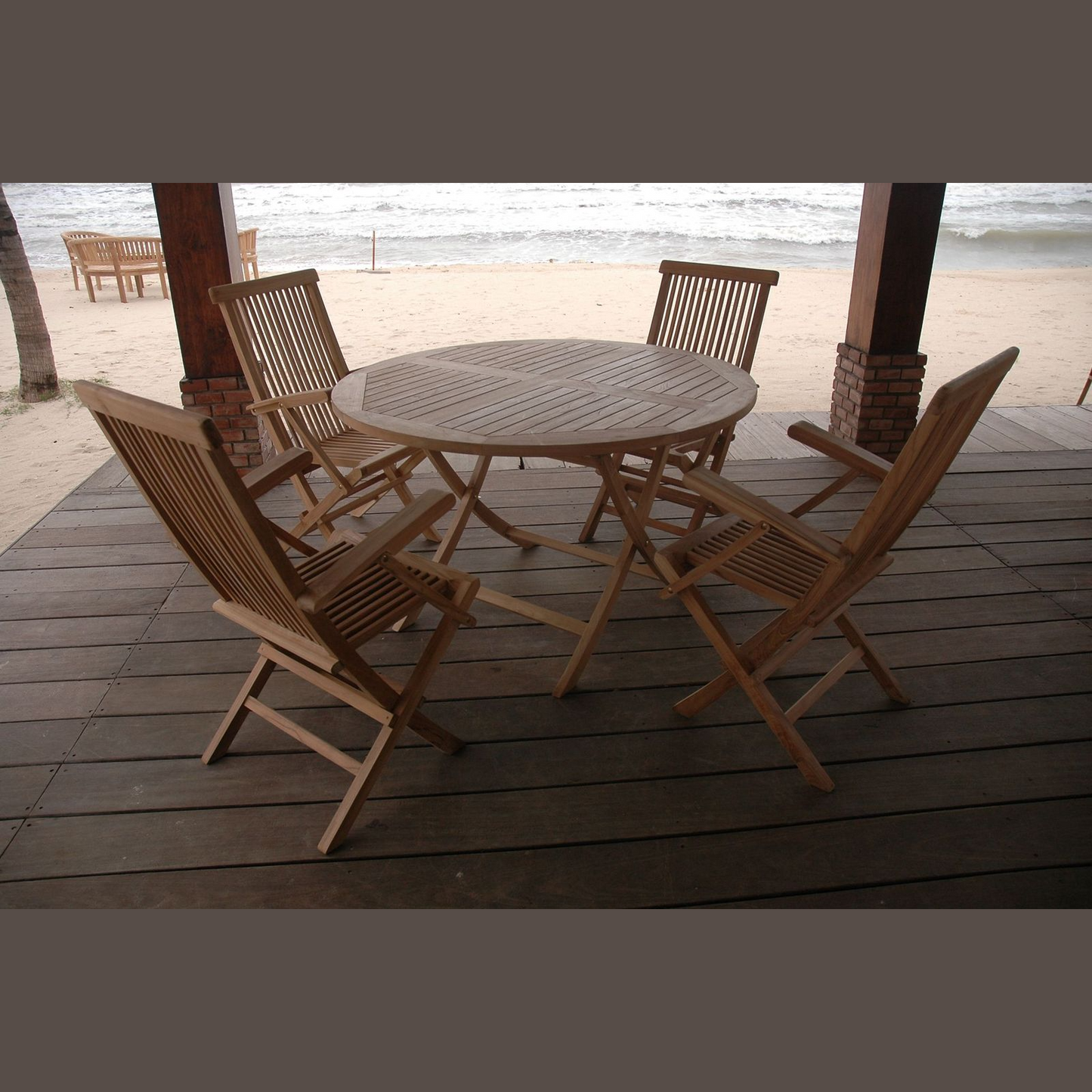 Wooden outdoor furniture set on a deck with a beach background