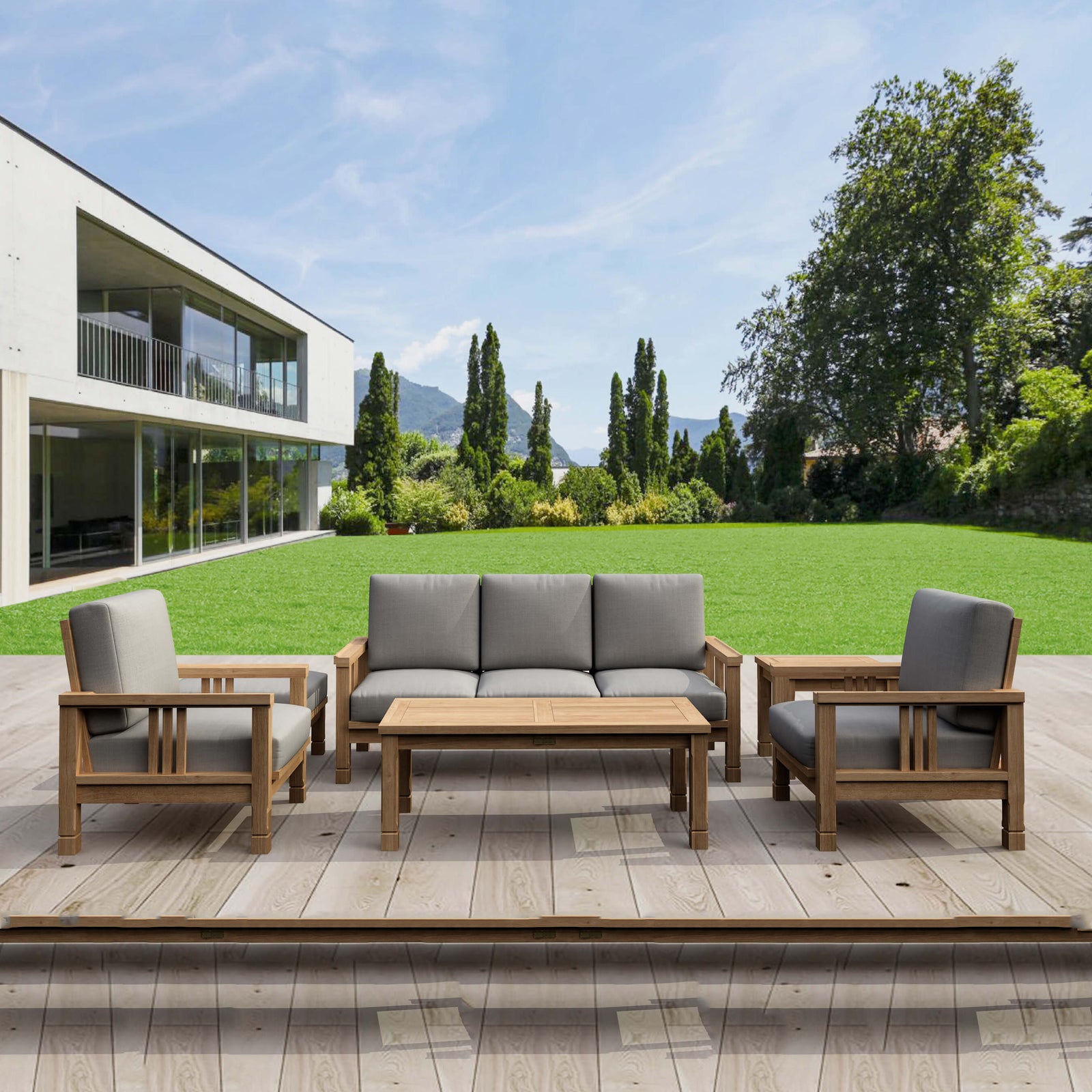 Outdoor patio set with gray cushions on a wooden deck in front of a modern house.