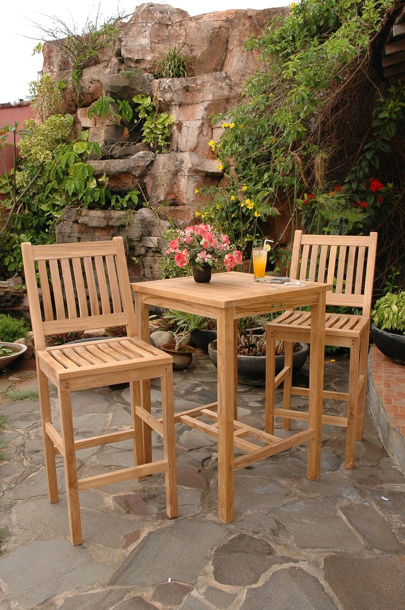 Outdoor patio set with wooden table and chairs on a stone patio.