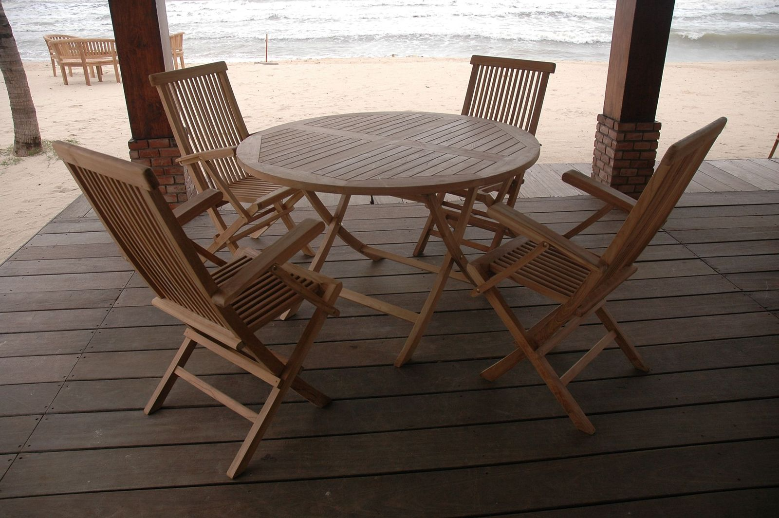 Wooden outdoor furniture set on a deck with a beach background