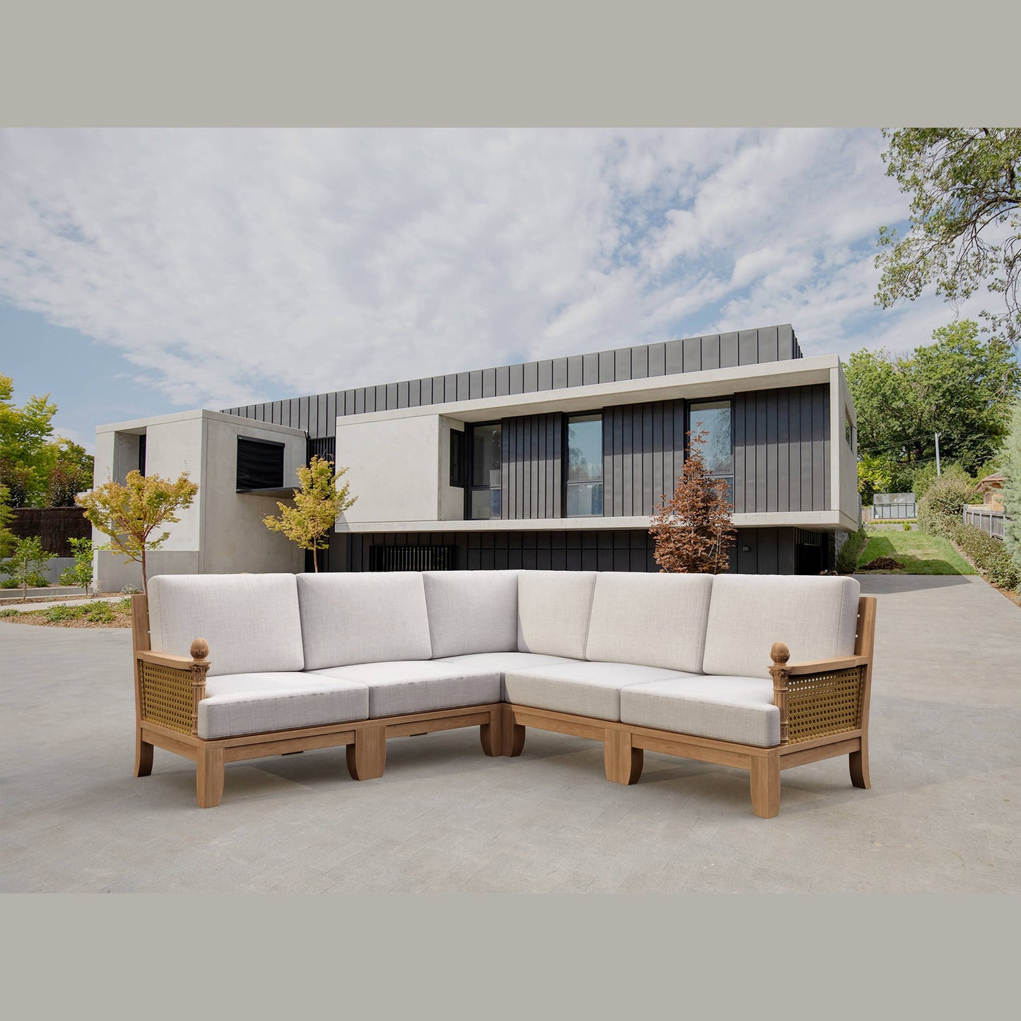 Sectional outdoor sofa with wooden frame and white cushions in front of a modern house.