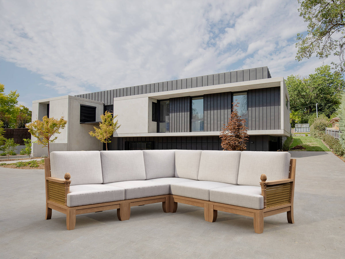 Sectional outdoor sofa with wooden frame and white cushions in front of a modern house.