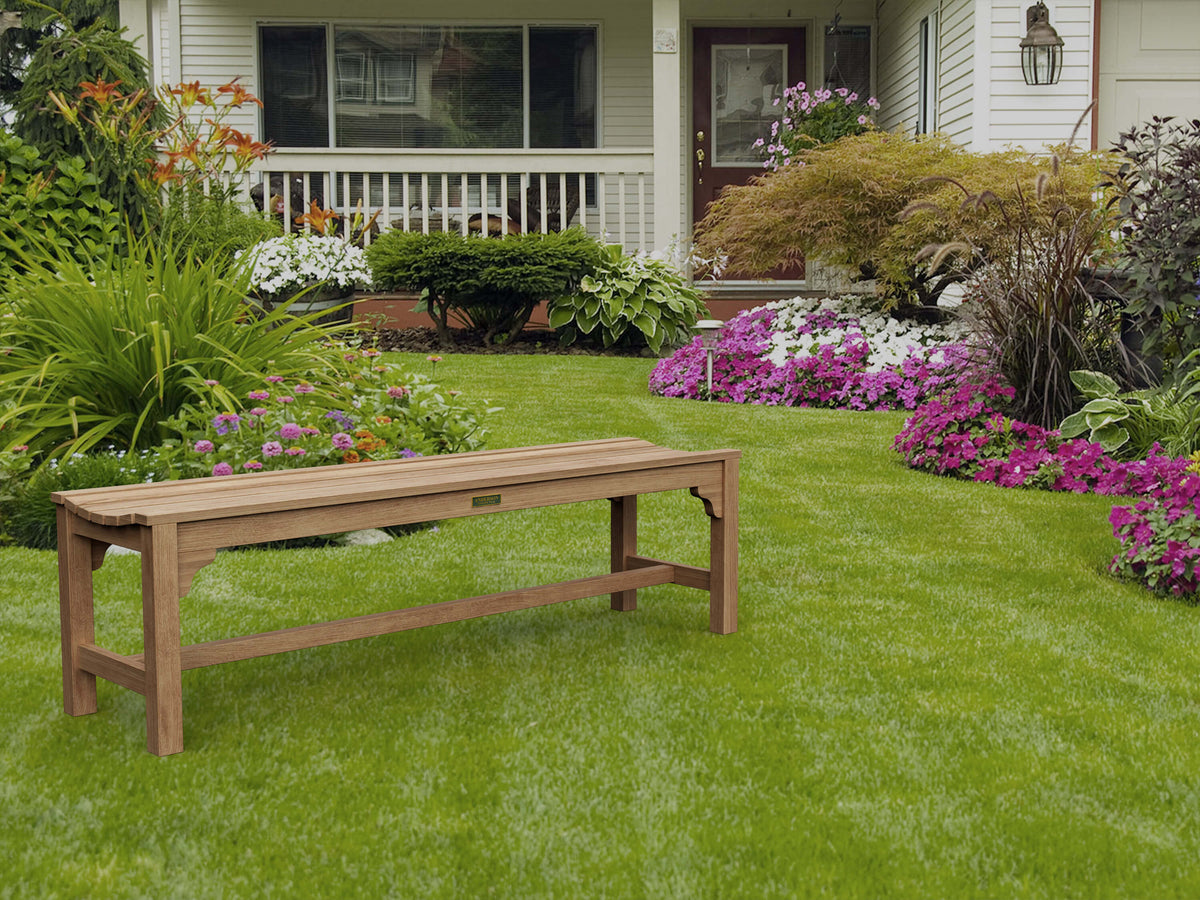 Wooden bench on a well-maintained lawn with flowers and a house in the background
