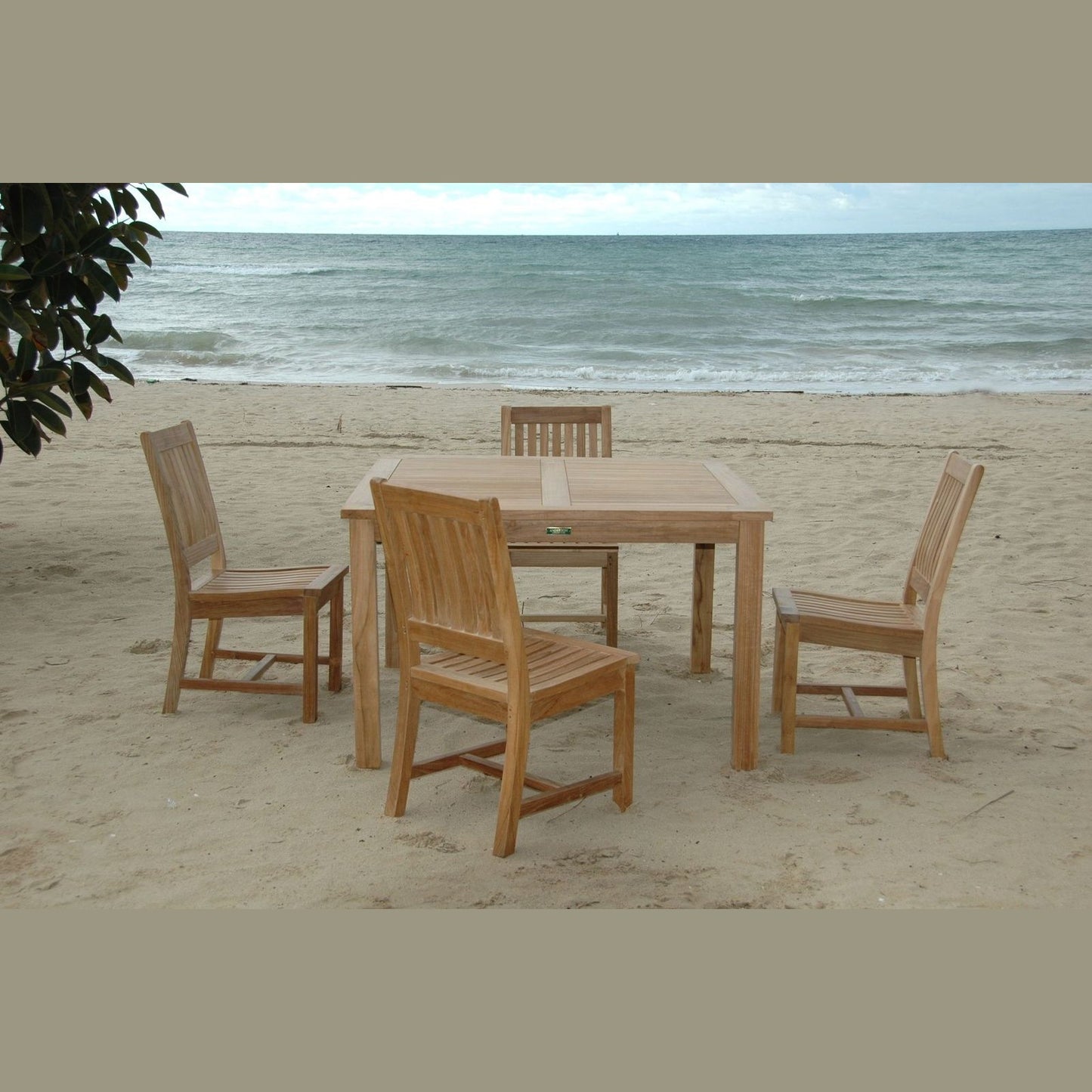 Wooden outdoor table and chairs on a sandy beach with ocean view