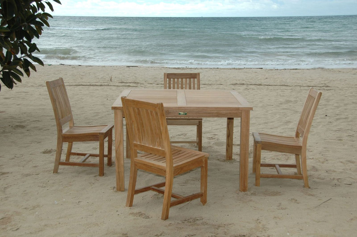 Wooden outdoor table and chairs on a sandy beach with ocean view