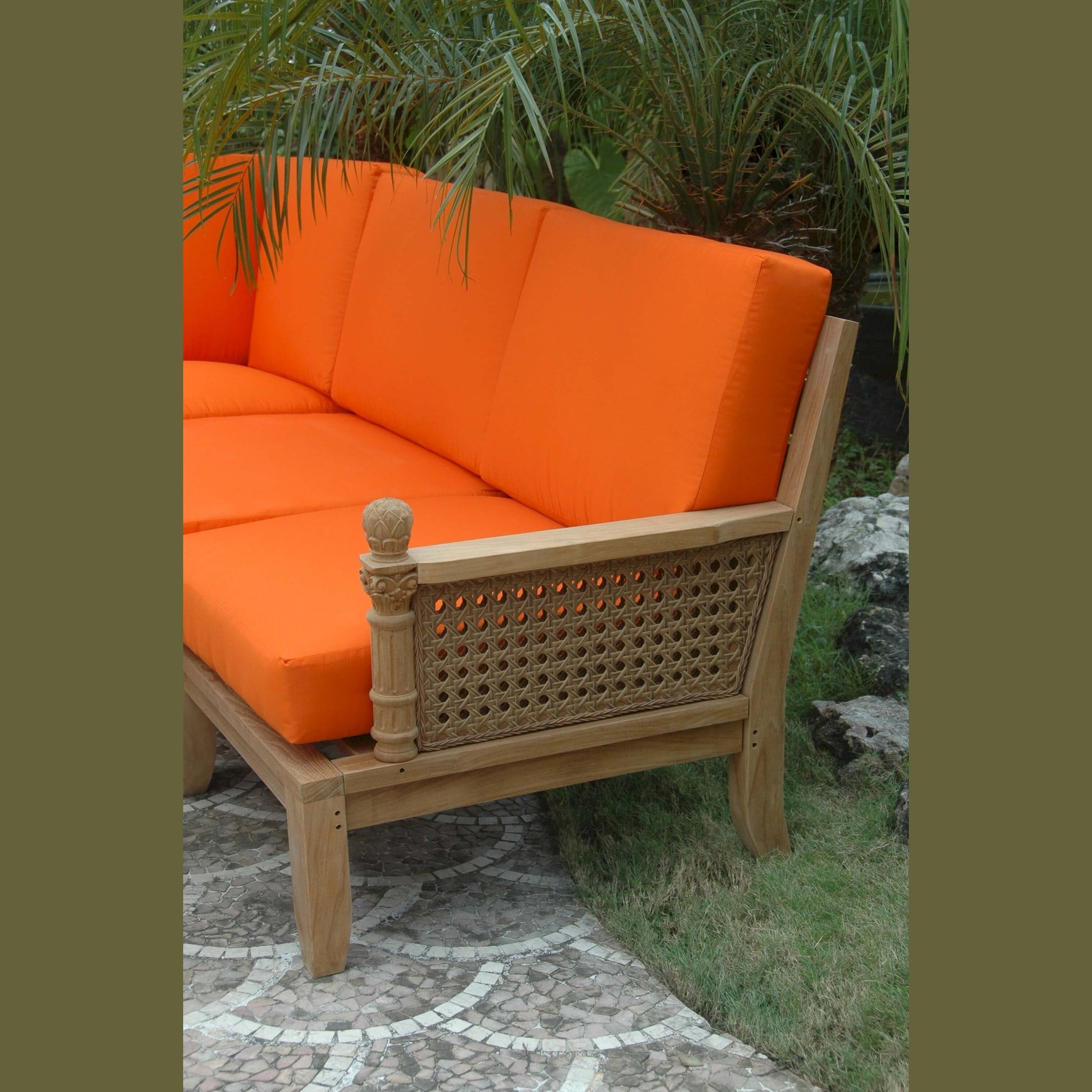 Orange cushioned outdoor sofa with wicker frame in a garden setting